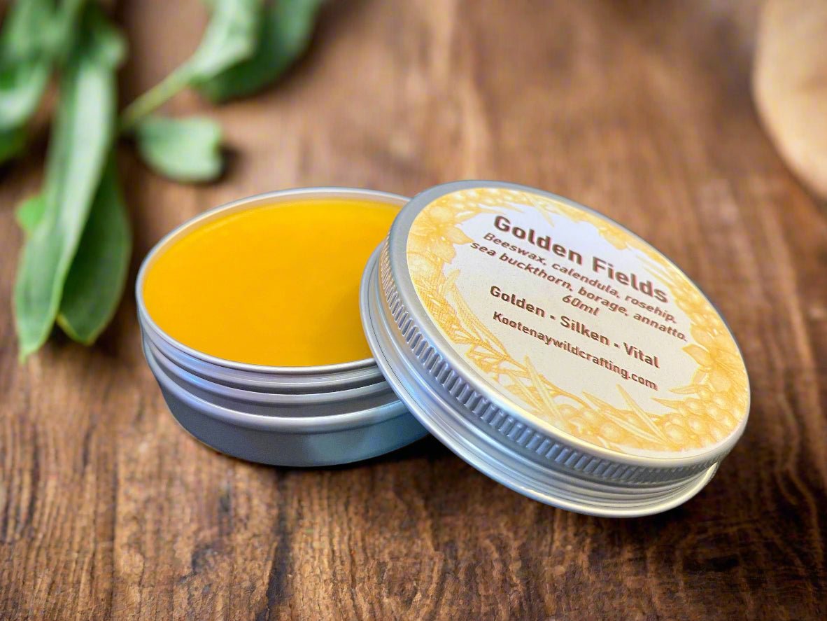 Yellow balm in a tin with a visible brand label on a wooden surface Kootenay Woman