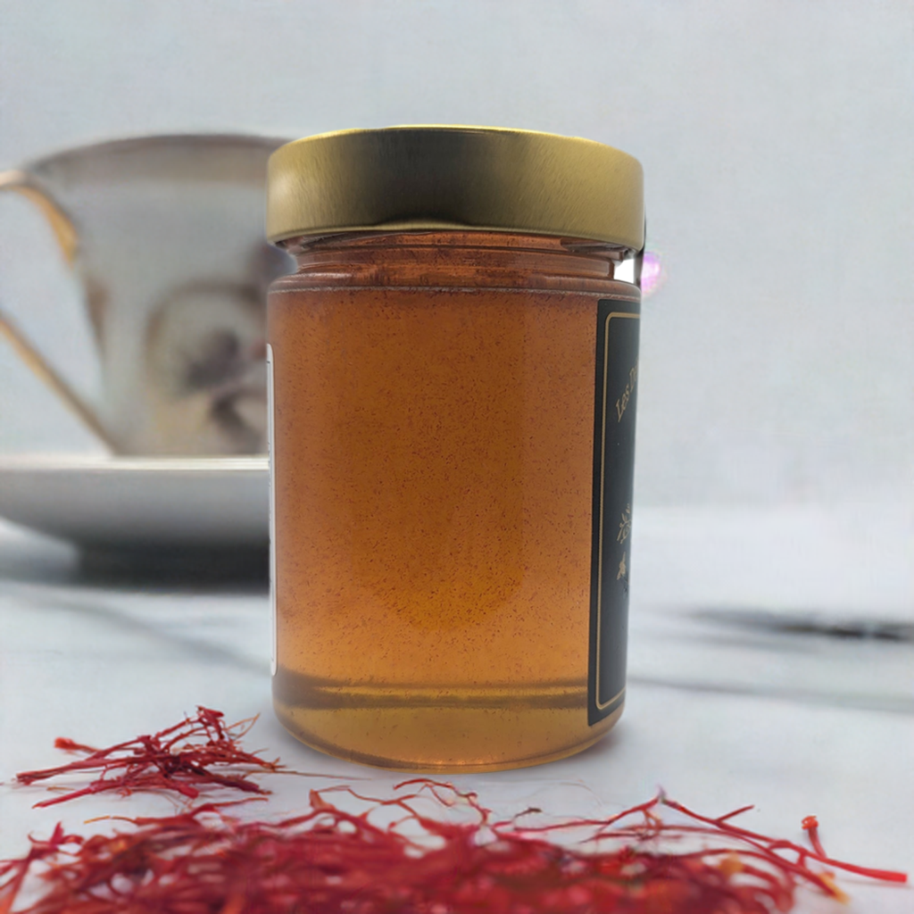 Jar of honey with a gold lid on a white surface with saffron strands.