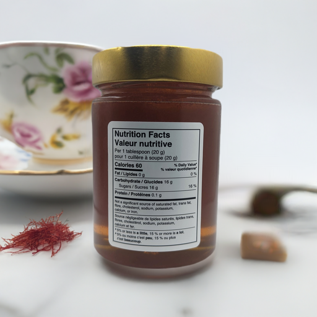 Jar of honey with a nutrition facts label on a white surface with a tea cup and saucer in the background.