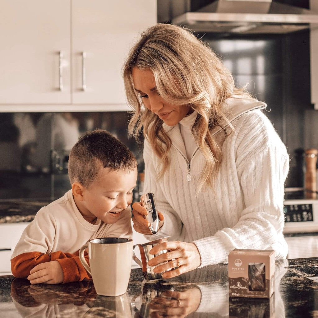 Woman and child in a kitchen preparing a drink together.