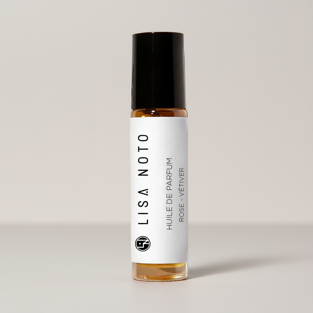 A small glass roller bottle of Lisa Noto Rose Vetiver perfume oil with a white label and black cap, set against a neutral light gray background.