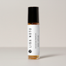 A small glass roller bottle of Lisa Noto Rose Vetiver perfume oil with a white label and black cap, set against a neutral light gray background.