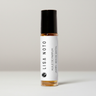 A small glass rollerball perfume bottle with amber liquid, a black cap, and a white label reading LISA NOTO and HUILE DE PARFUM JASMIN - BOIS DE SANIAL, centered on a light gray background.