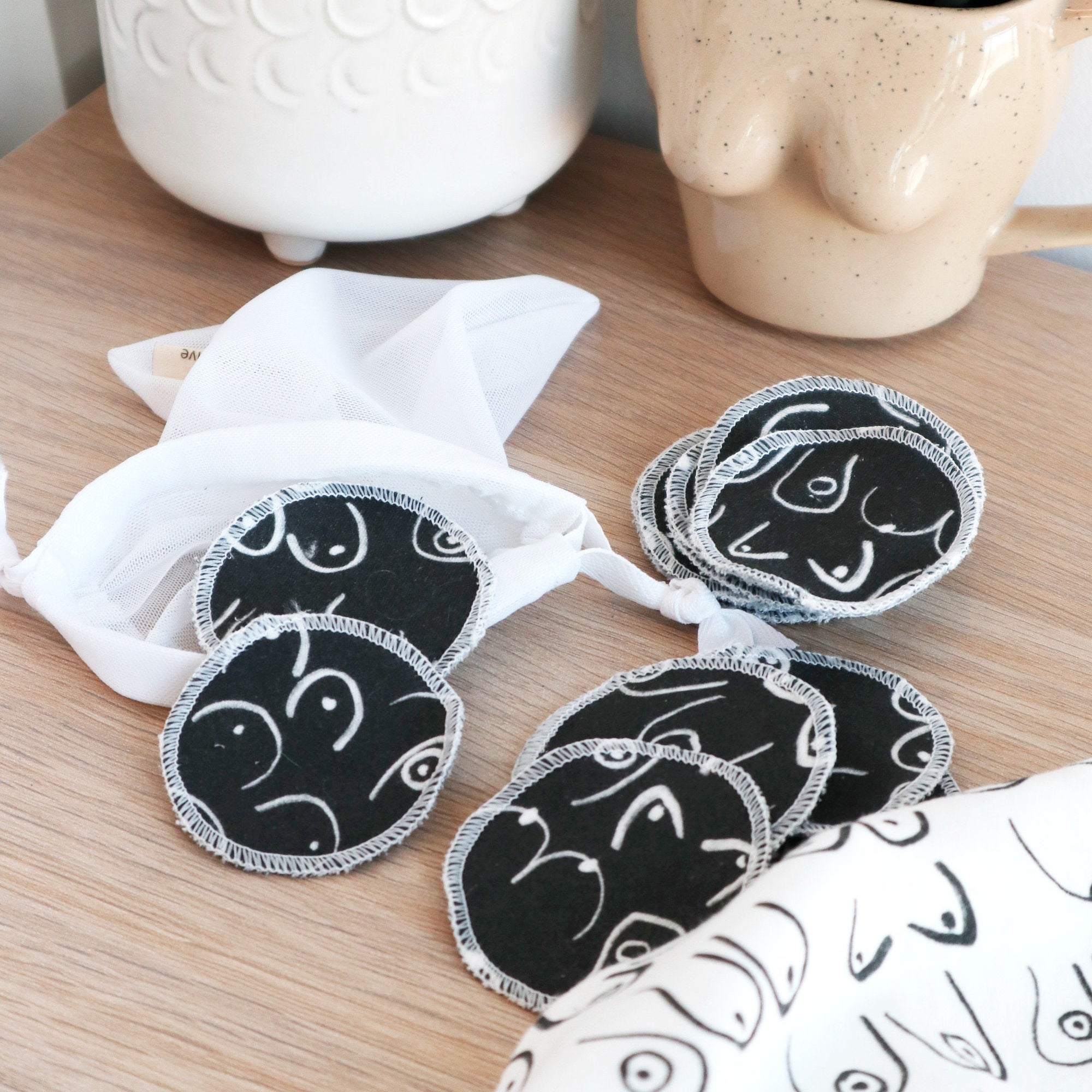 Black and white resuable cotton makeup pads on a white cloth by Freon Collective with makeup brushes