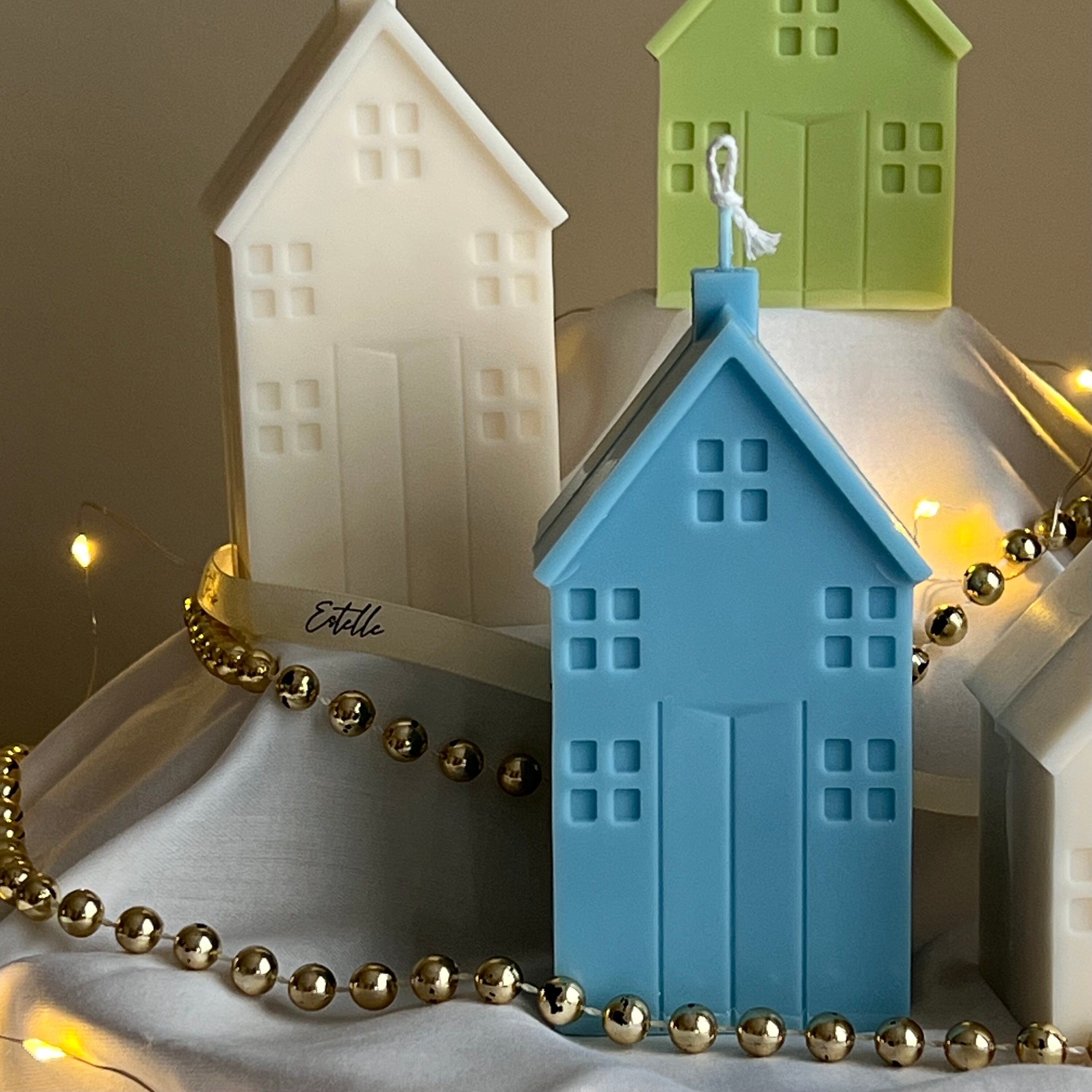 Colorful house-shaped candles with string lights on a neutral background detail