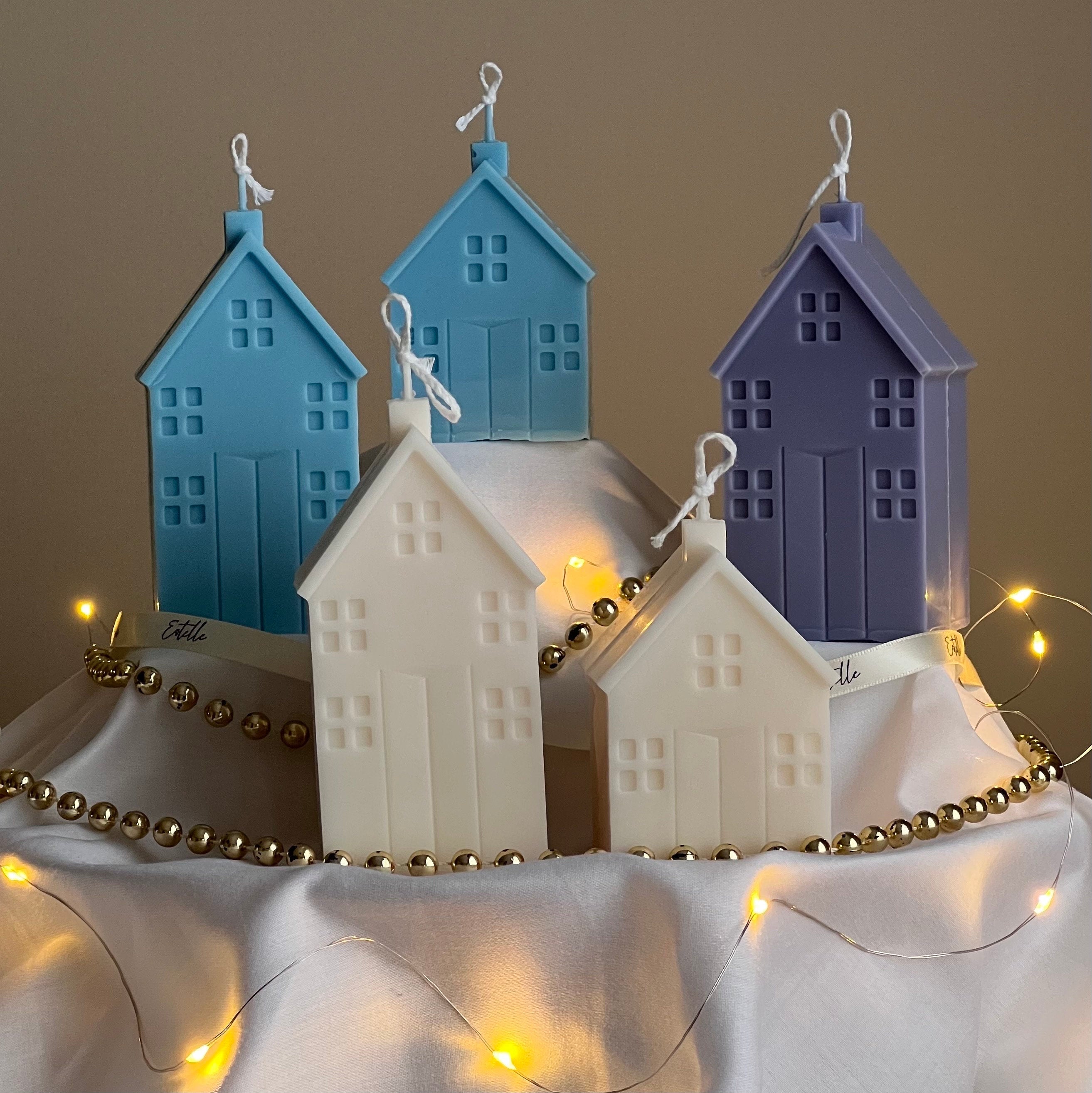 Decorative house-shaped candles with string lights on a neutral background