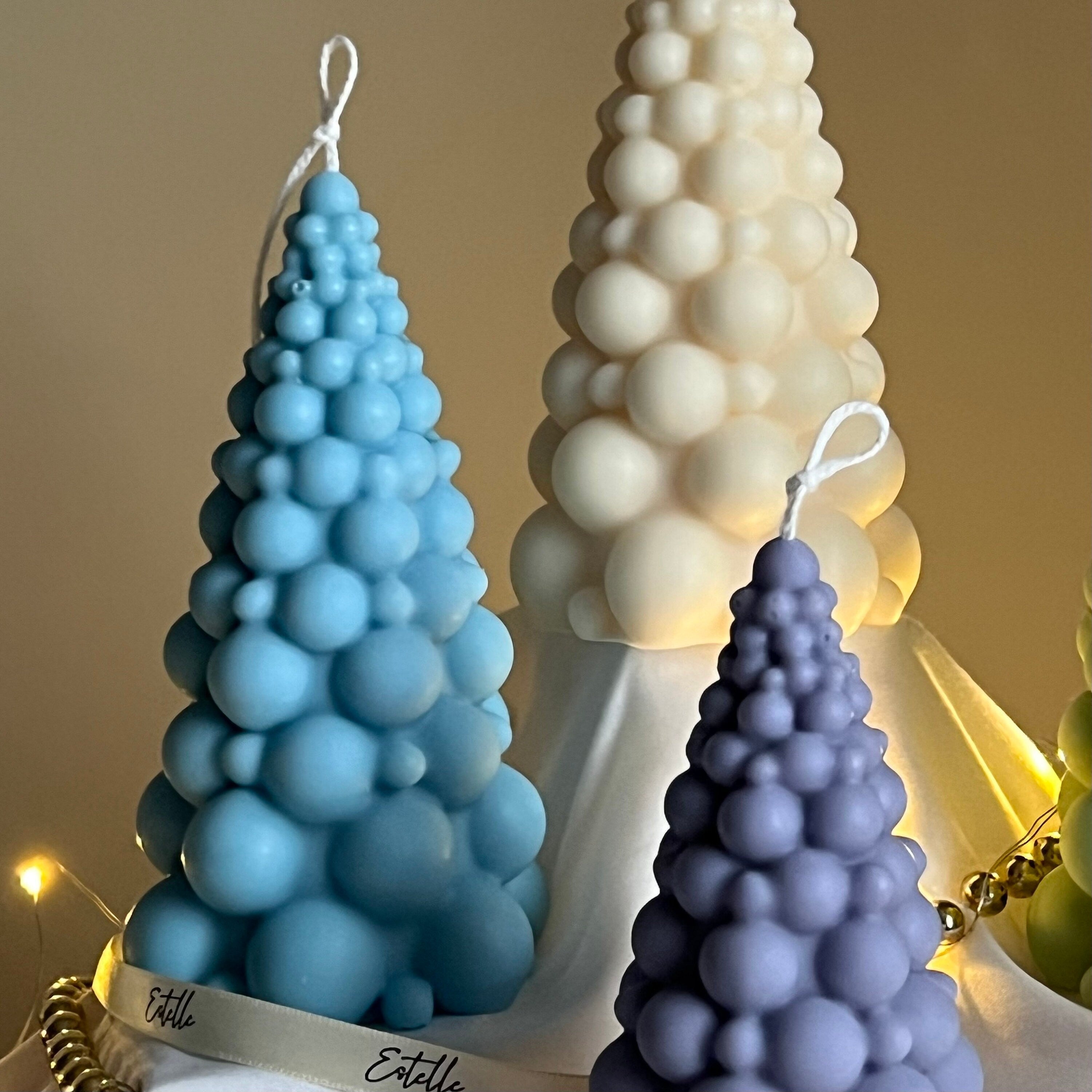 Three bubble-shaped candles in blue, white, and purple on a neutral background.