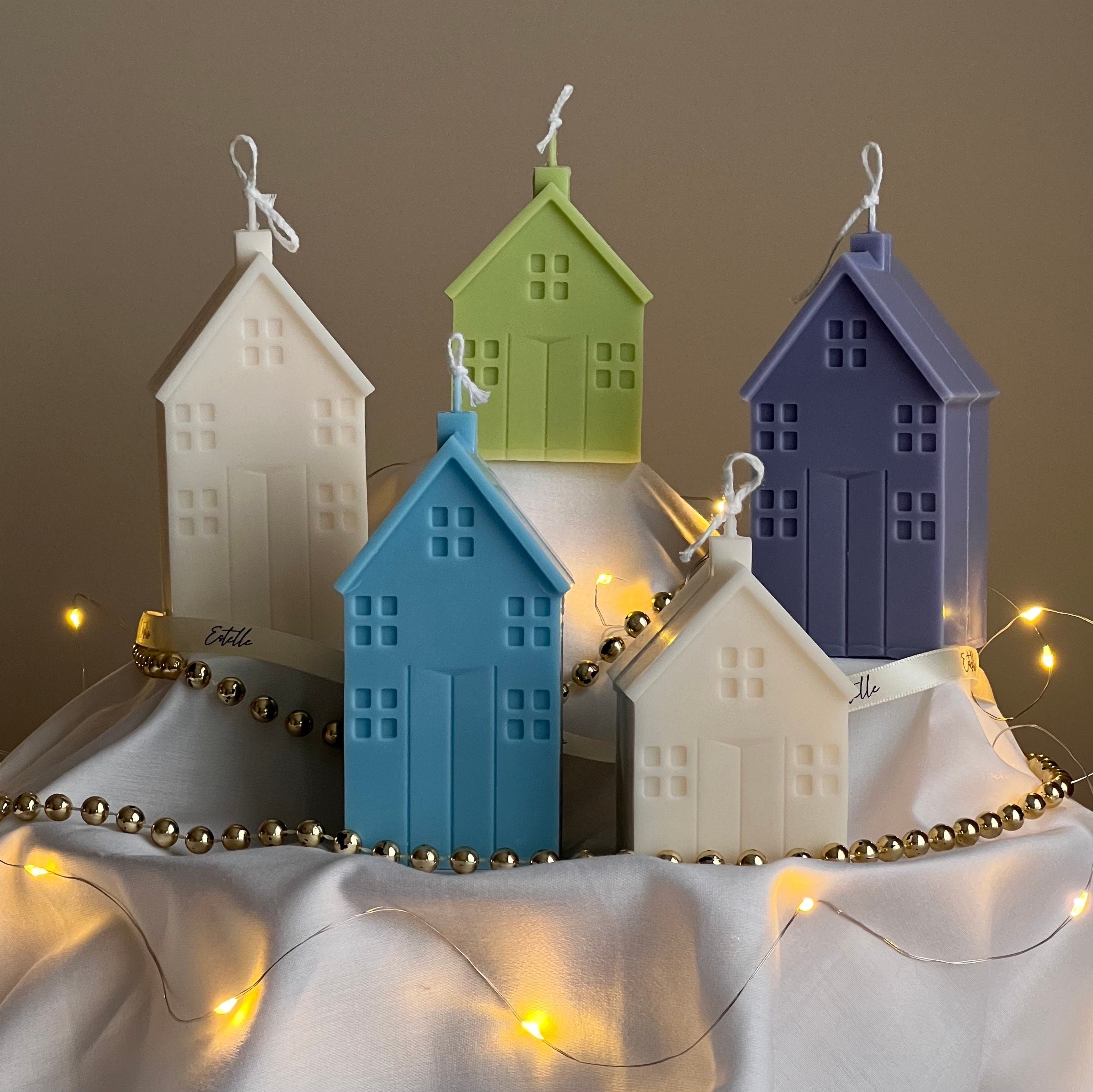 Colorful house-shaped candles with string lights on a neutral background