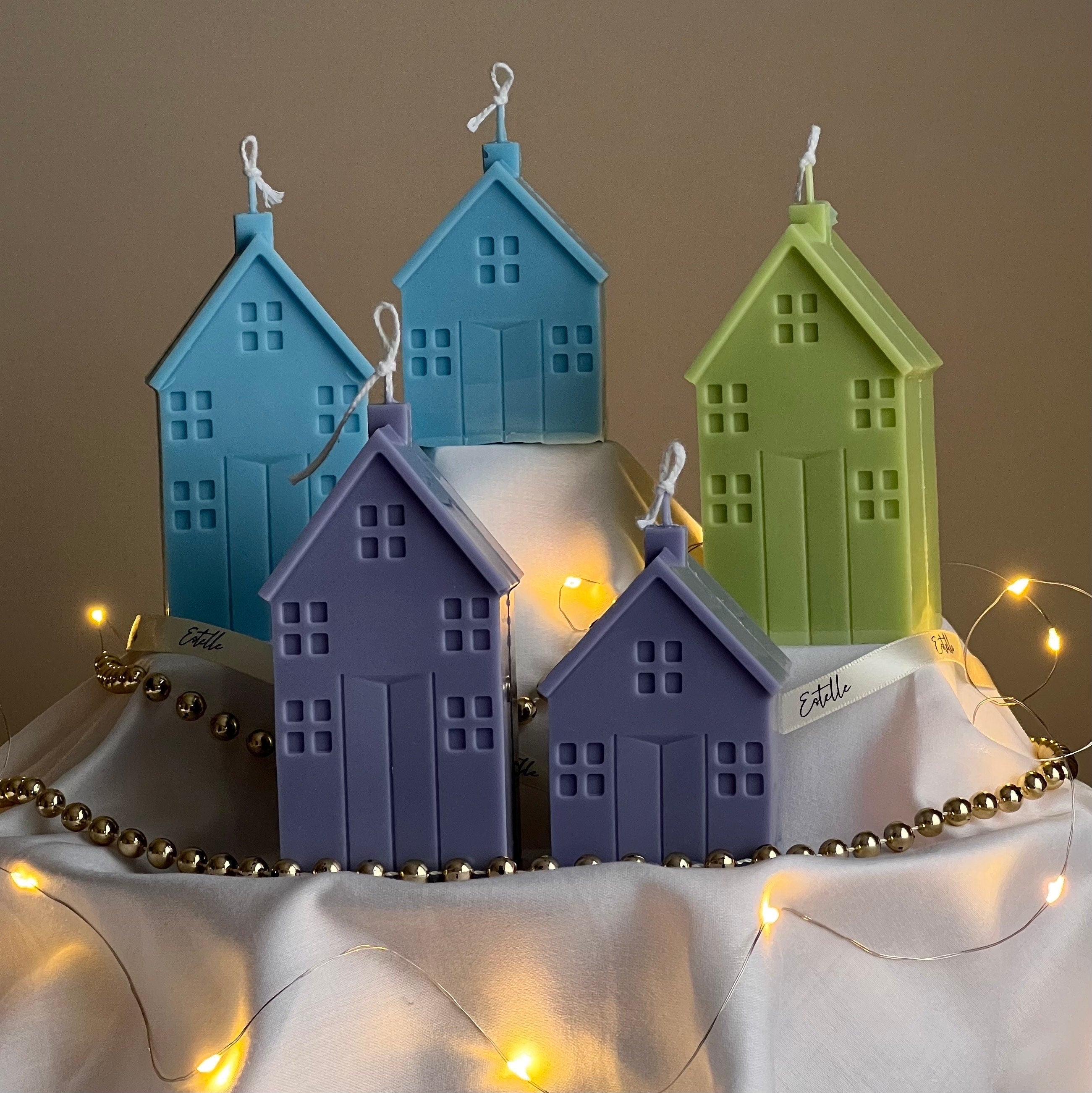 Set of colorful house-shaped candles with string lights on a neutral background