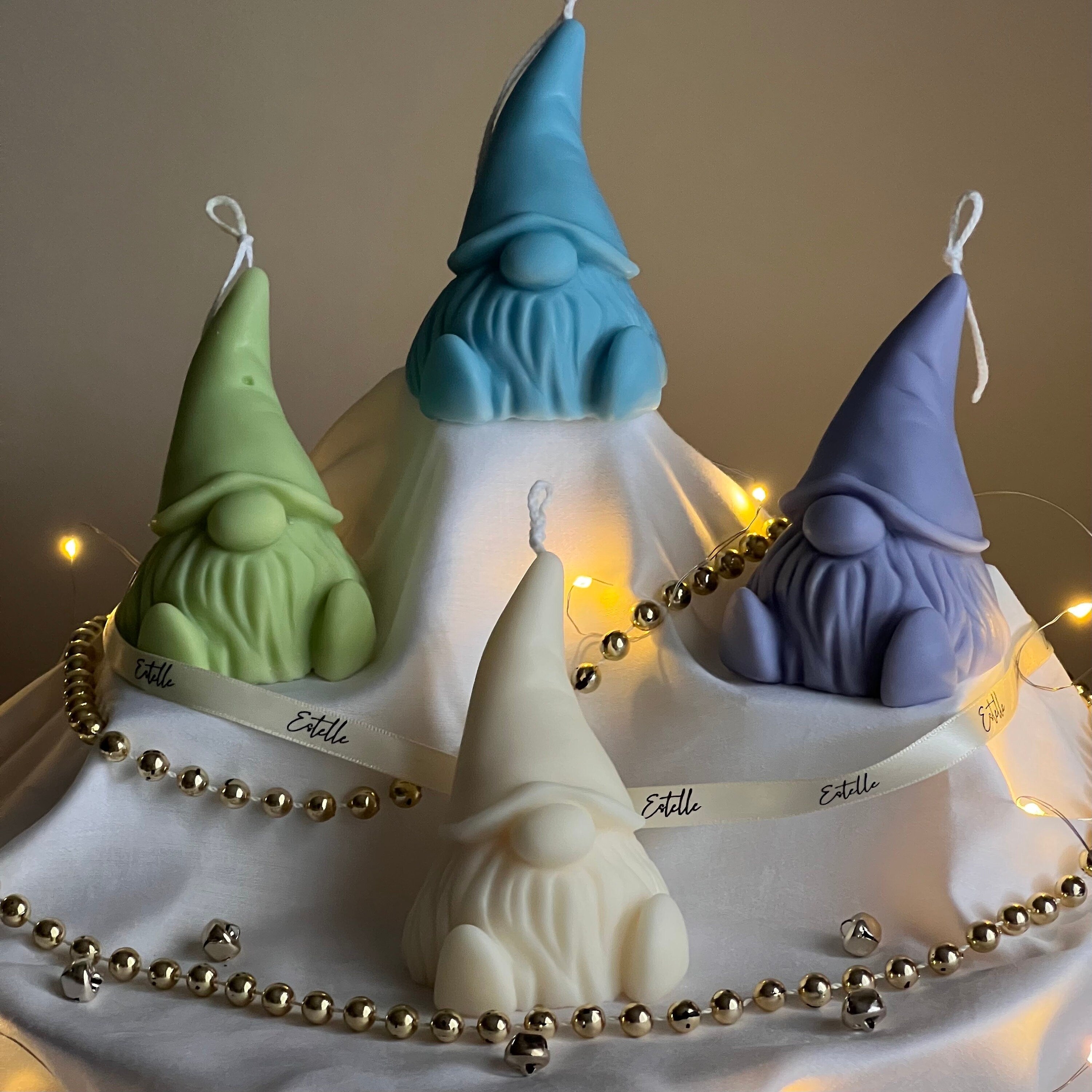 Four gnome-shaped candles on a cake with decorative lights and beads.