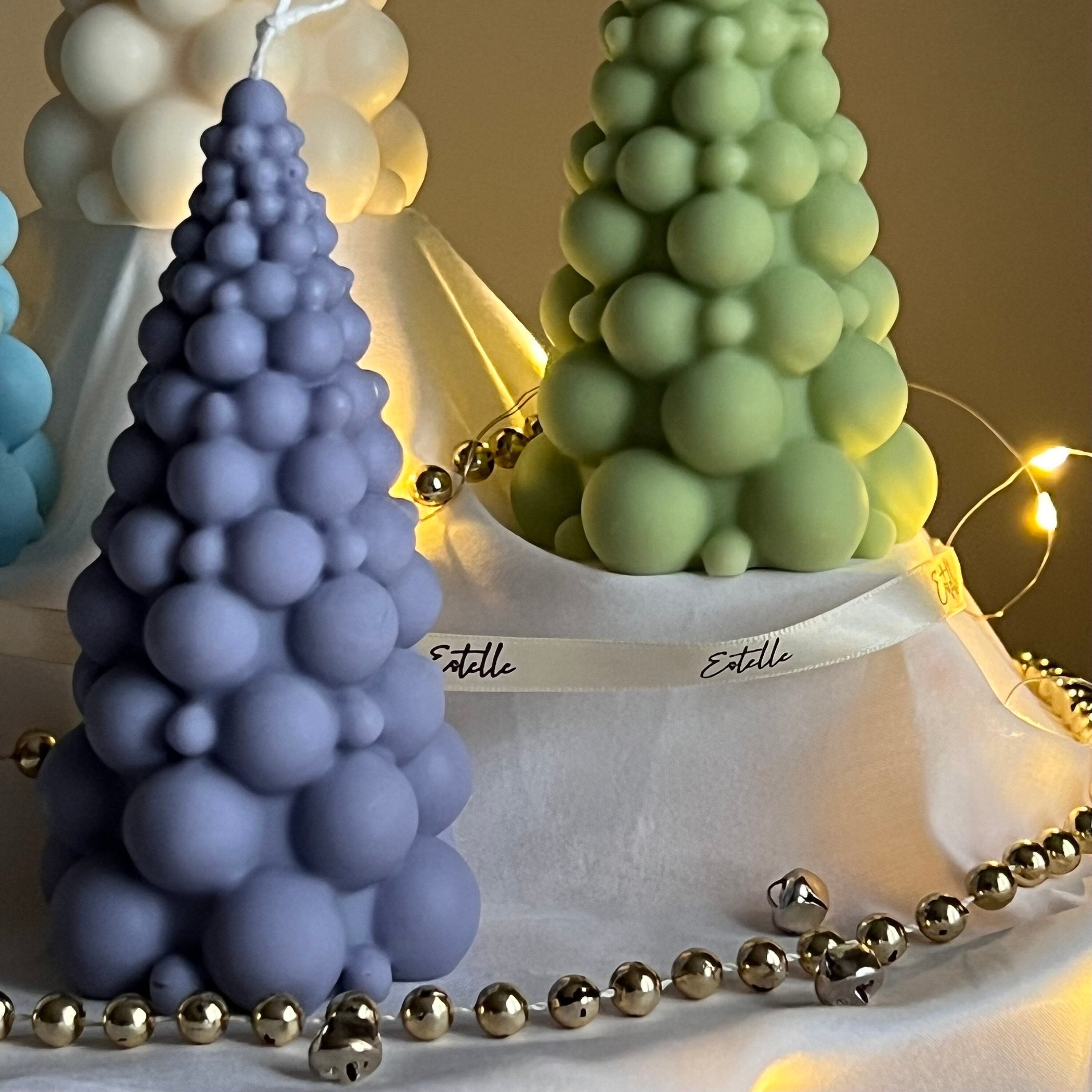 Decorative bubble-shaped candles in purple and green with a white bag labeled 'Estelle' in the background.