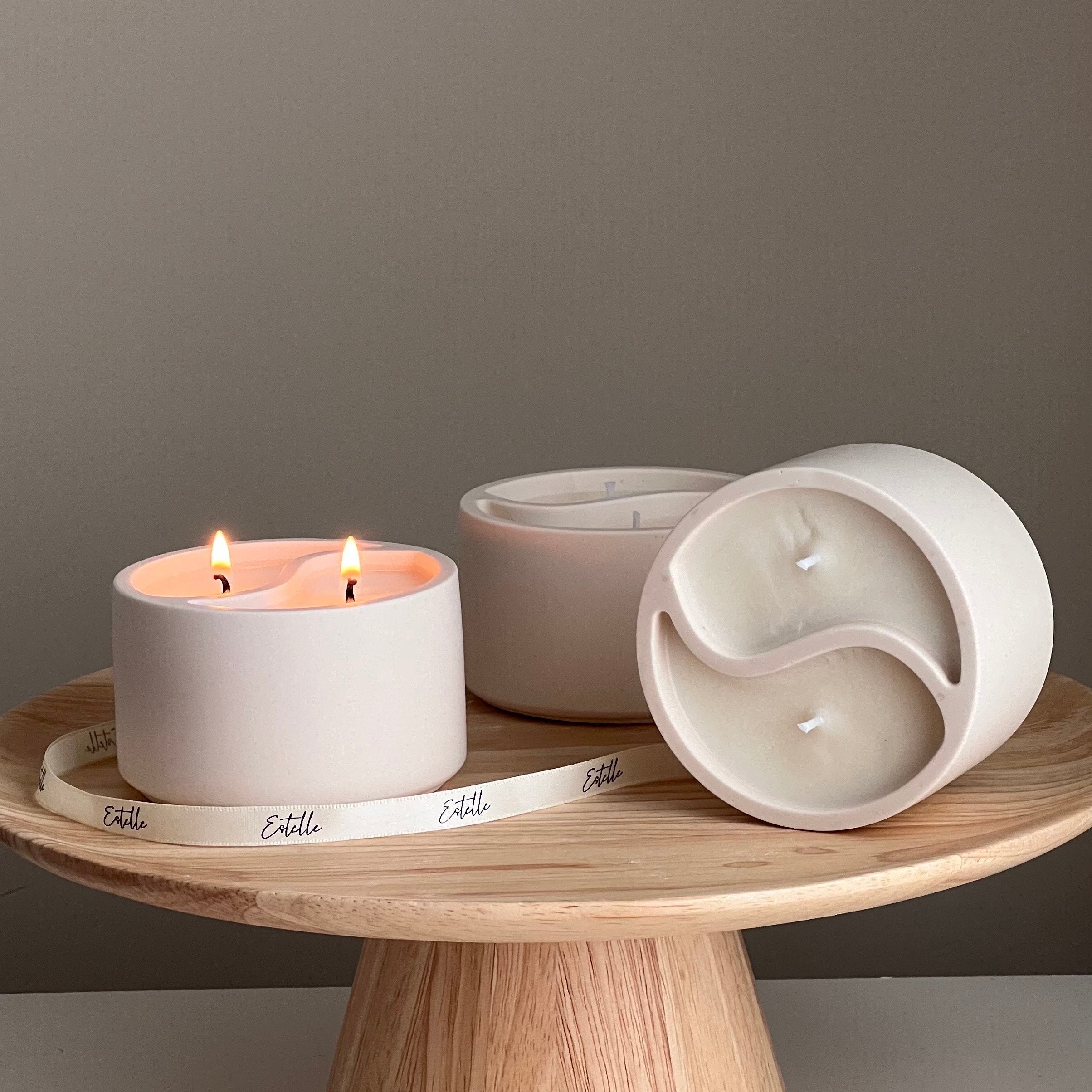Three white ceramic candles on a wooden stand with a neutral background