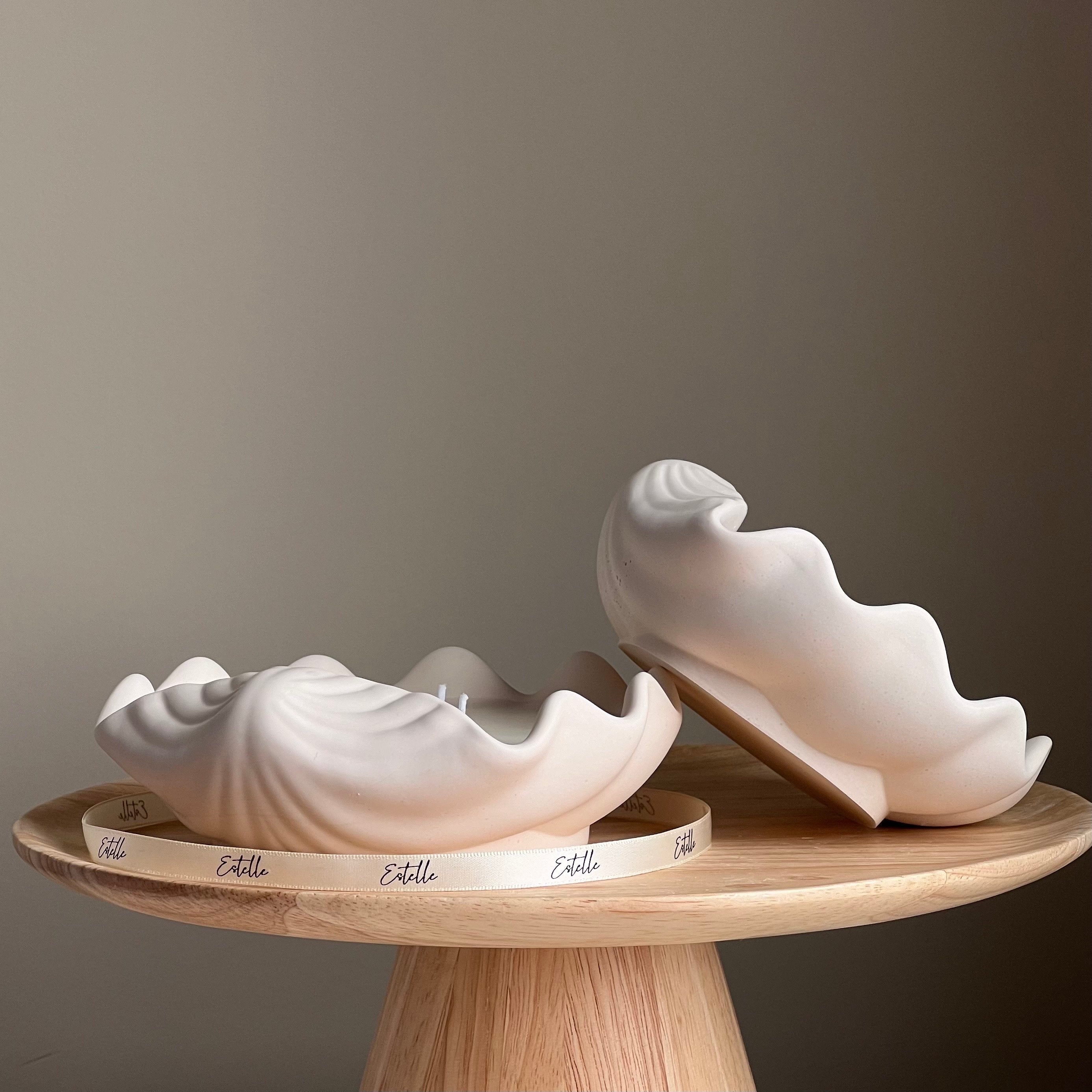 White ceramic shell-shaped objects on a wooden stand against a gray background