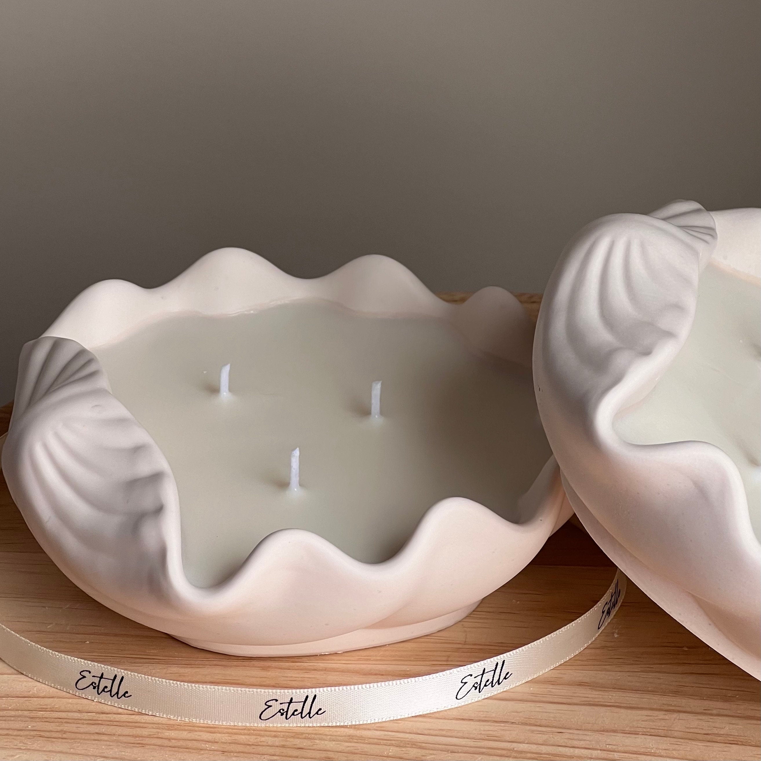 Shell-shaped candle with three wicks on a wooden surface, branded 'Estelle'.