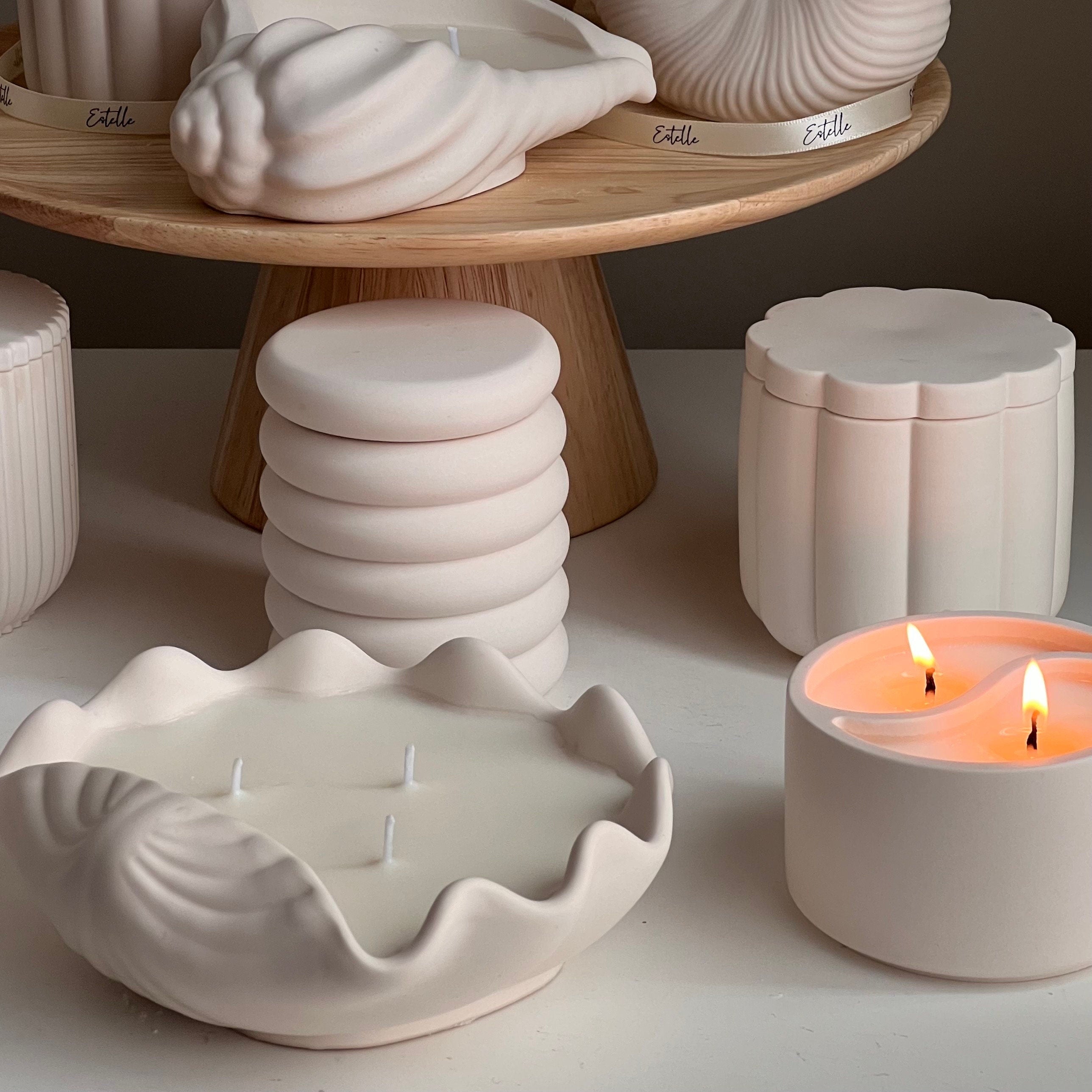 Ceramic containers and a lit candle on a neutral background