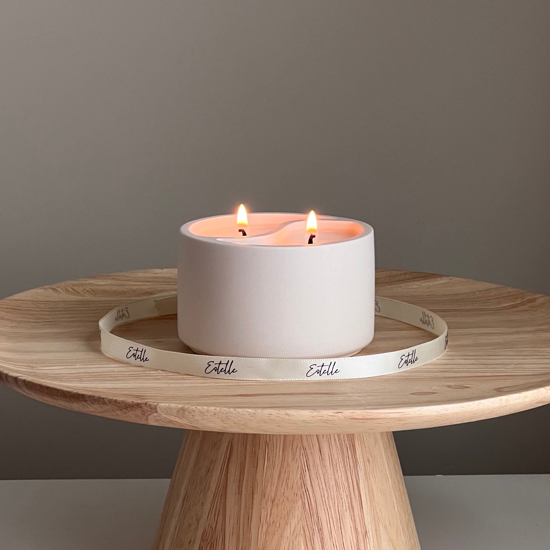 White candle in a decorative holder on a wooden table with a gray background