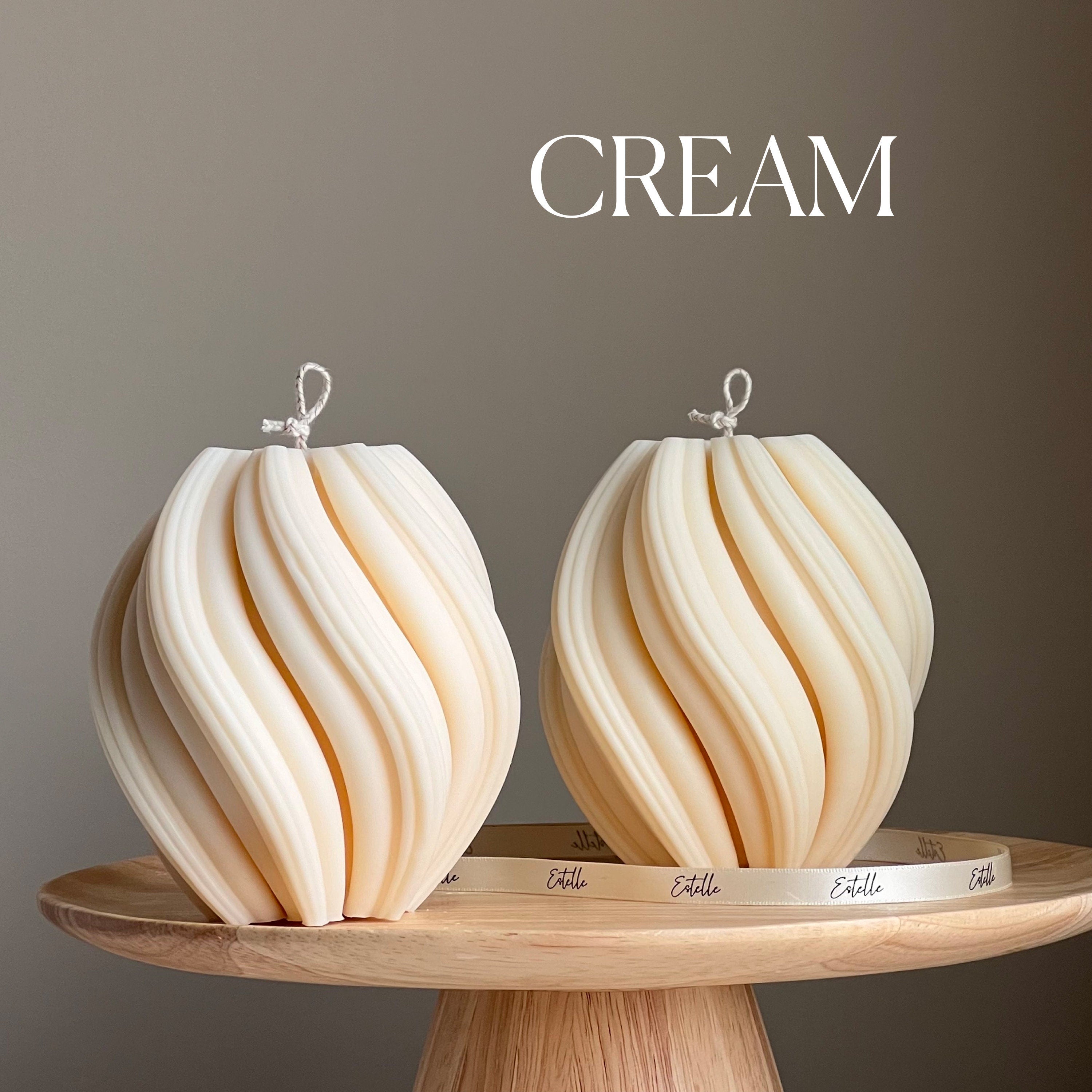 Two cream-colored decorative items on a wooden stand with 'CREAM' text above.