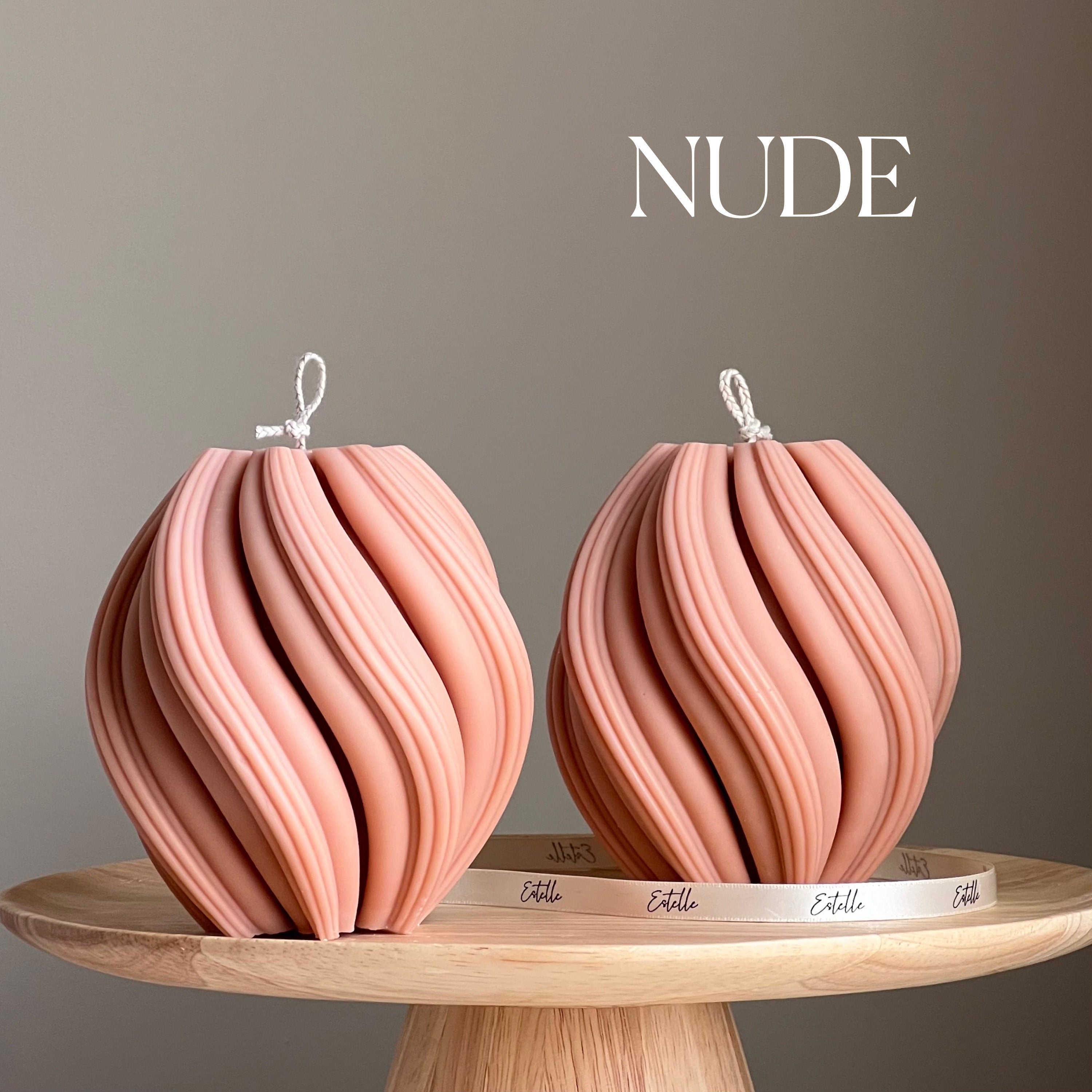 Two pink decorative items on a wooden stand with 'NUDE' text above.