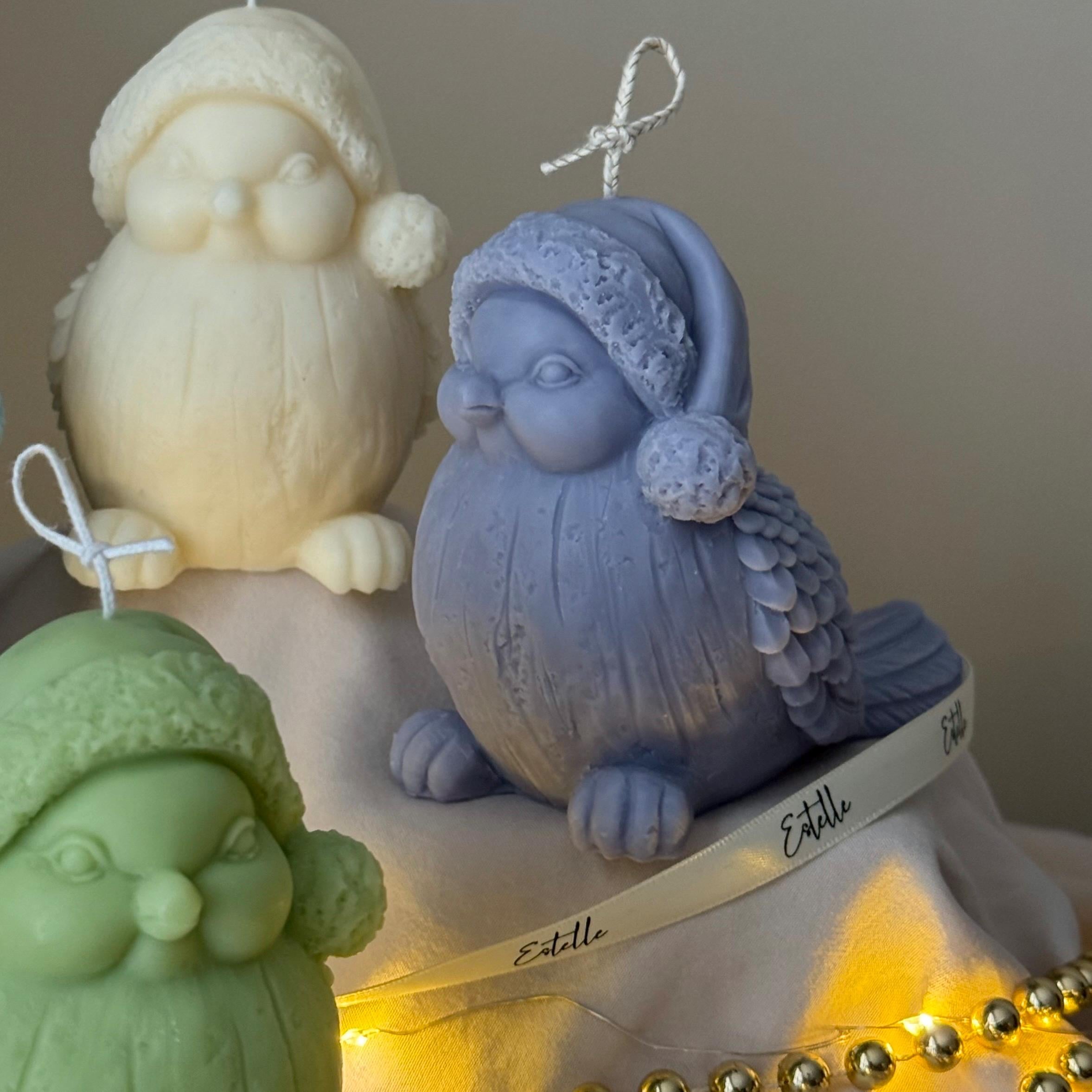 Three decorative candles shaped like birds  with pom-poms on a neutral background.