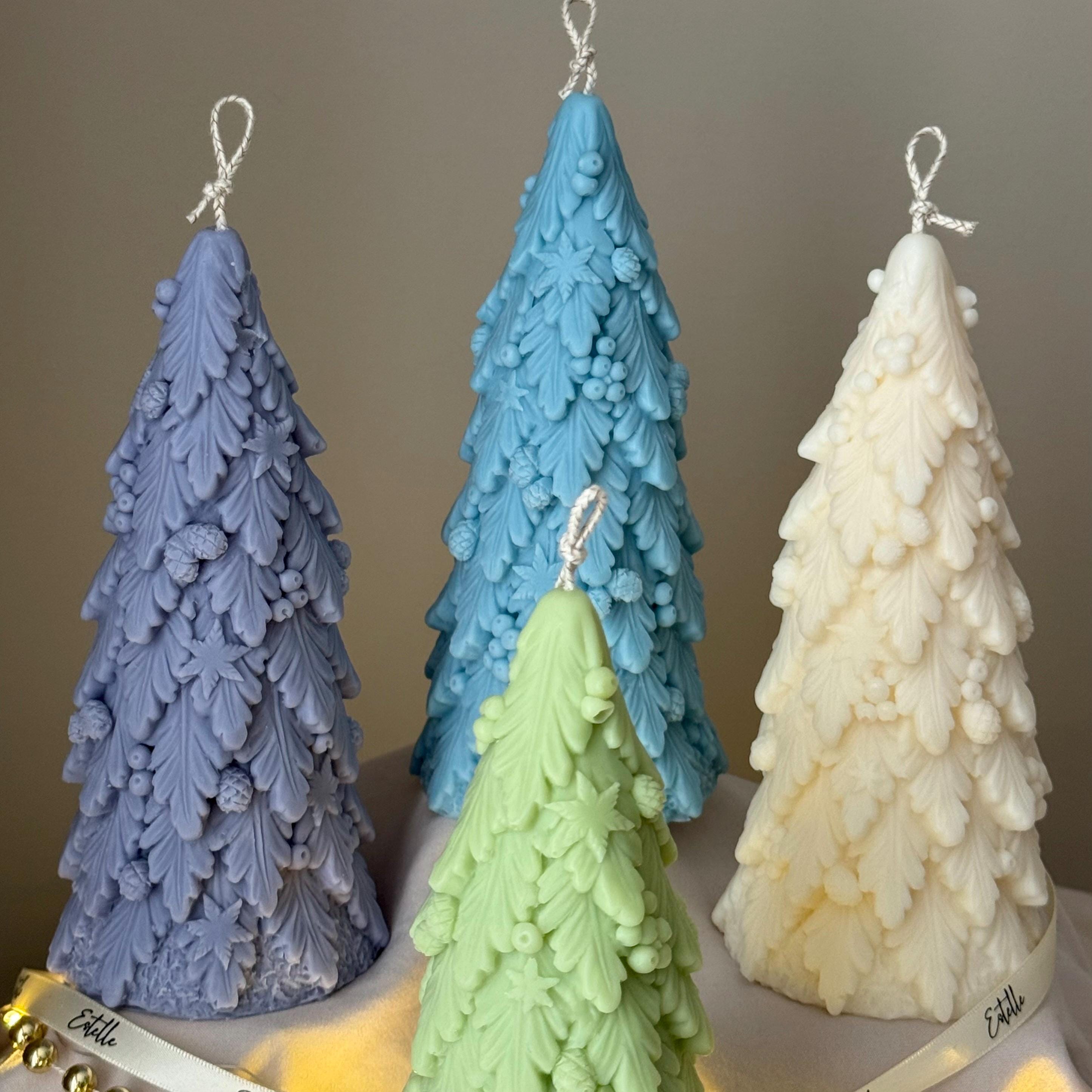 Four Christmas tree-shaped candles in blue, green, and white on a neutral background.
