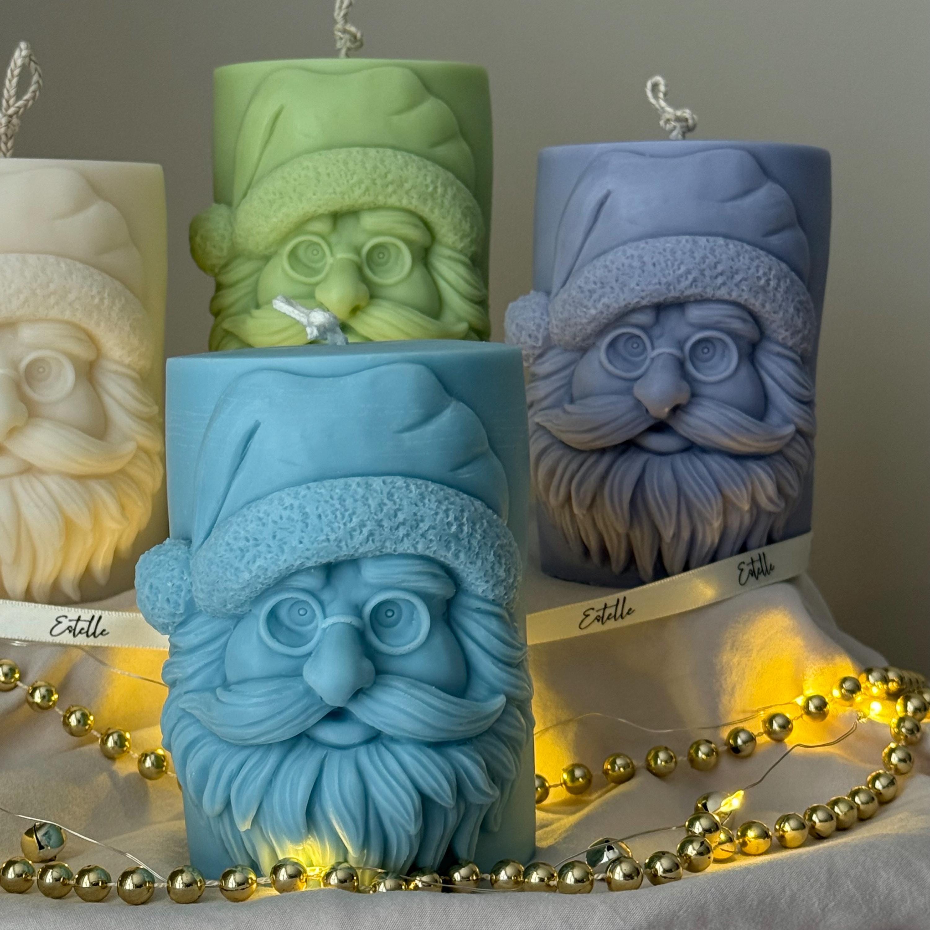Four candles with Santa Claus faces on a gray surface with string lights from Estelle Studios