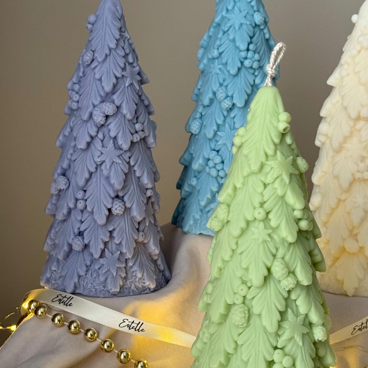 Tree-shaped candles in various colors on a neutral background