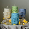 Four candles with Santa Claus faces on a gray surface with string lights from Estelle Studios