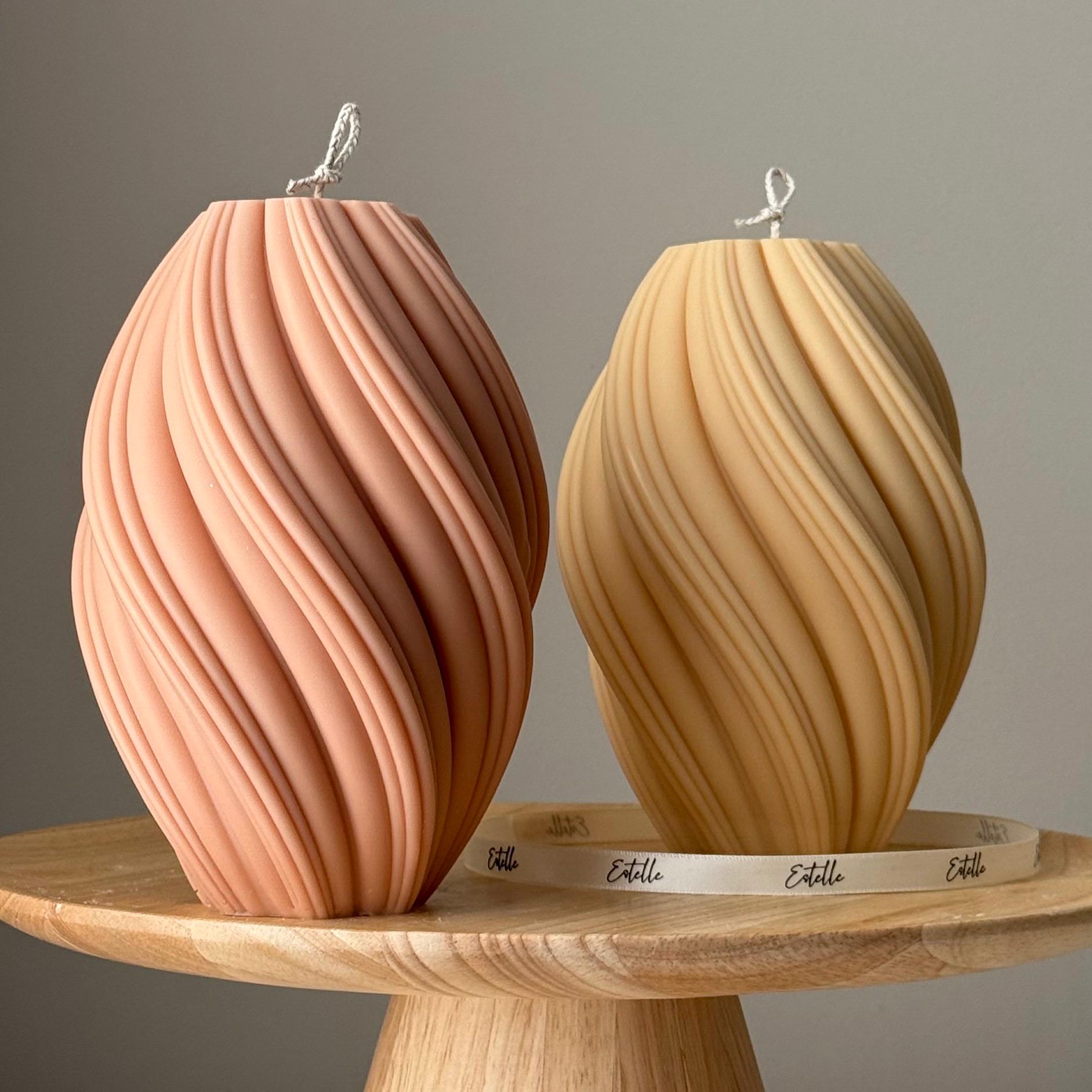 Two textured hand poured soy was candles on a wooden stand with a neutral background