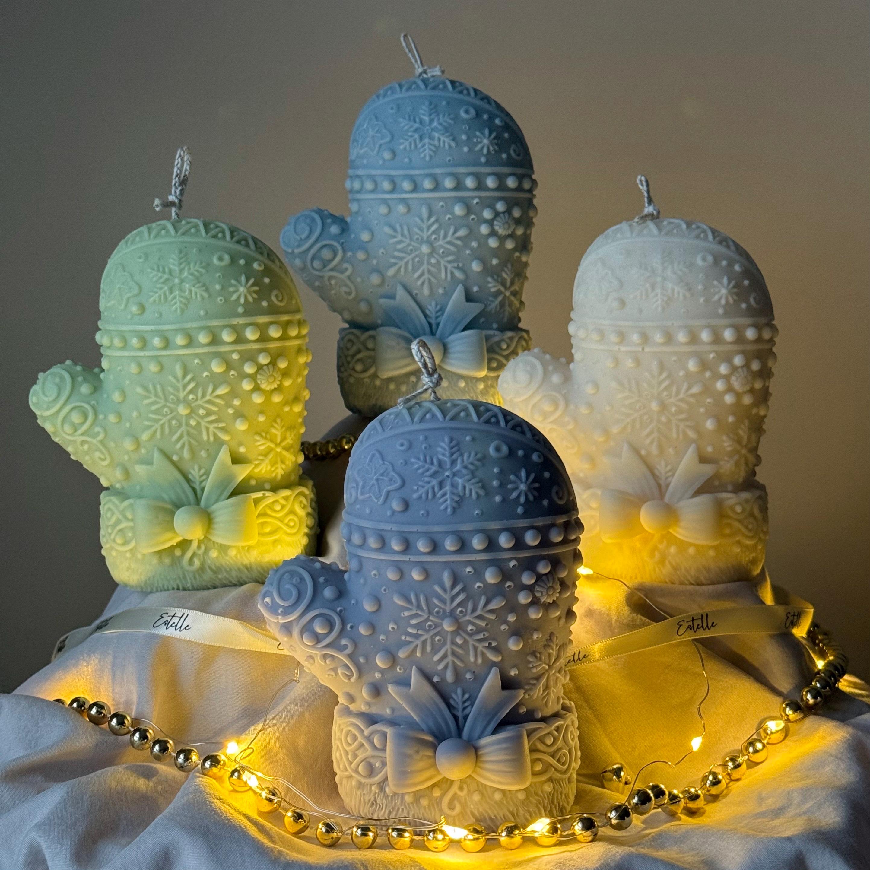 Four colors of Decorative snowflake mitten candles with bow accents on a soft background.