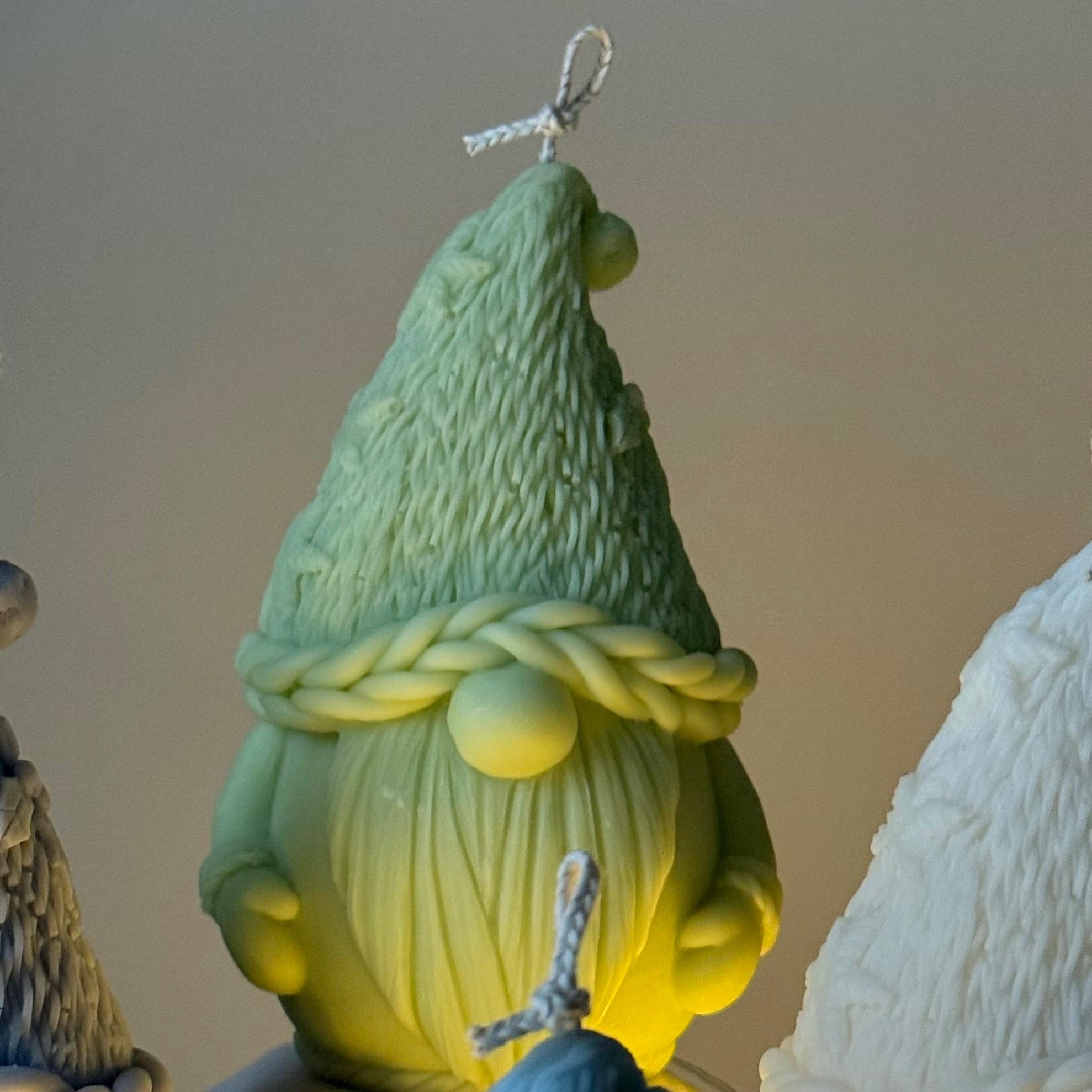 Green gnome-shaped candle with braided hat on a plain background
