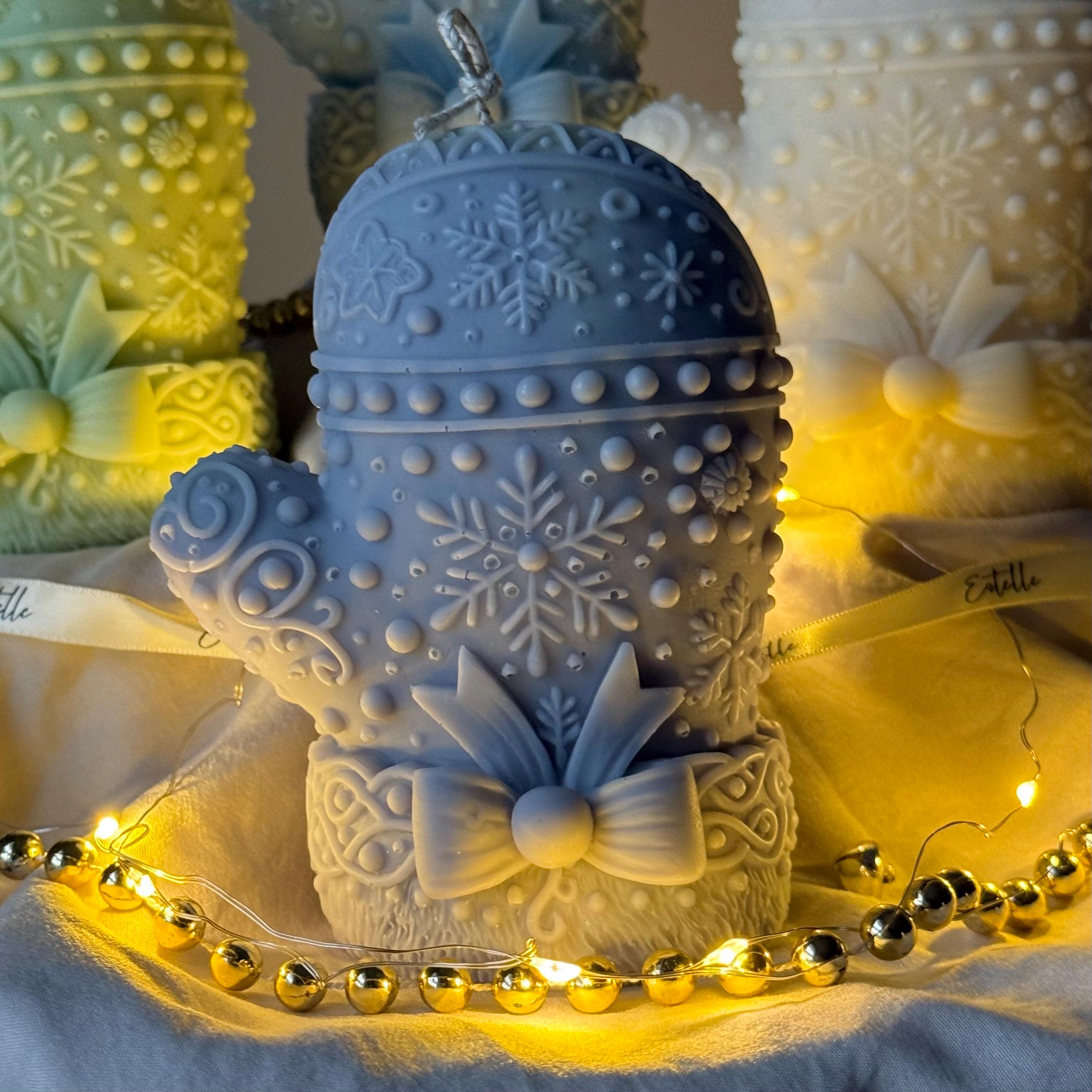 Blue Decorative snowflake mitten candles with bow accents on a soft background.