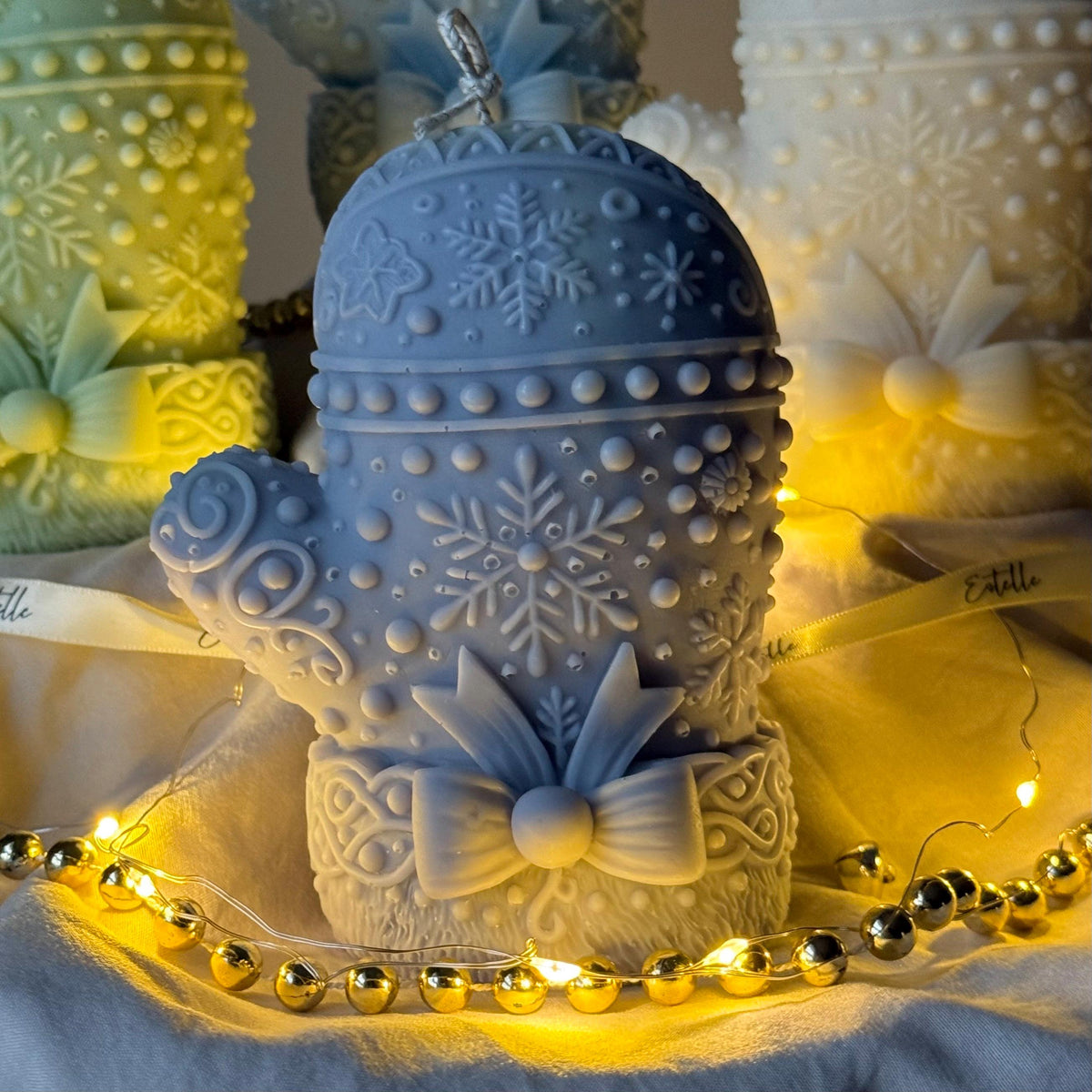 Blue Decorative snowflake mitten candles with bow accents on a soft background.