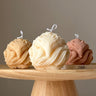 Three decorative candles shaped like ice cream scoops on a wooden stand with a neutral background.