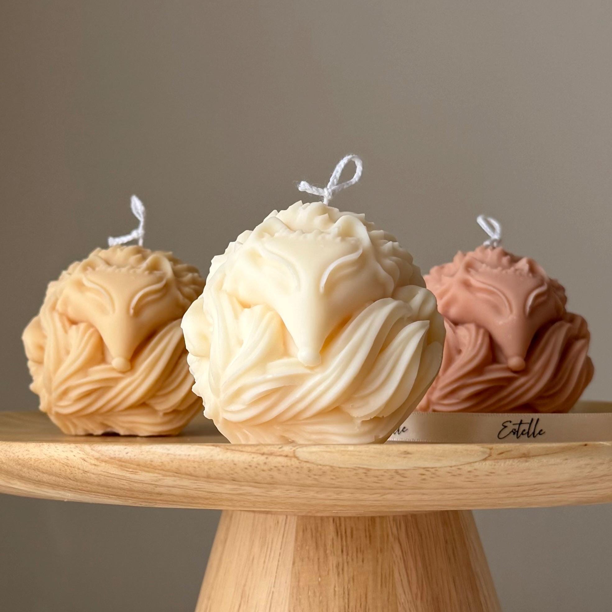 Three decorative candles shaped like ice cream scoops on a wooden stand with a neutral background.