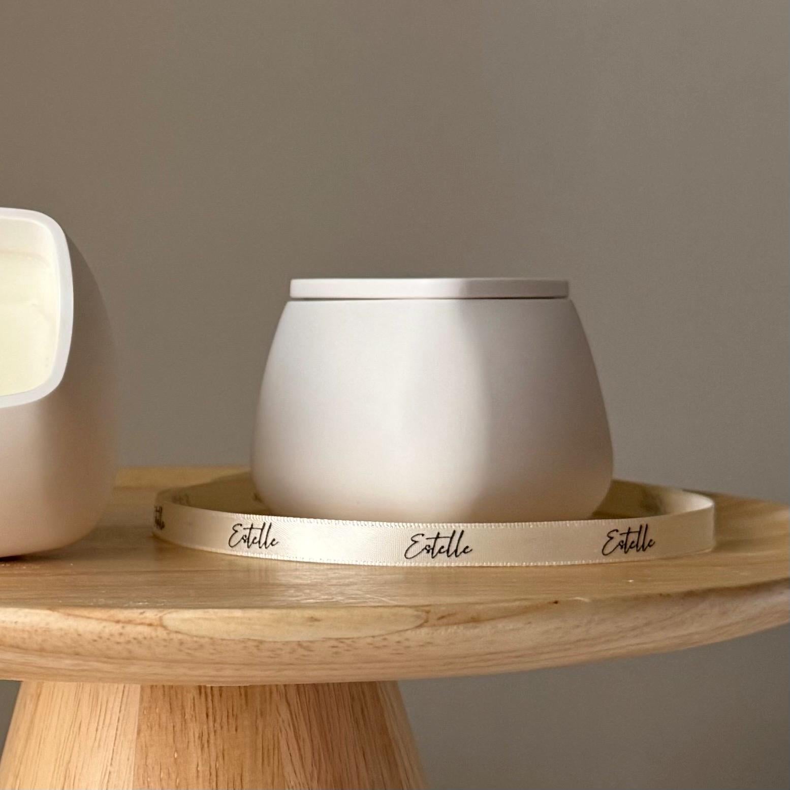 White ceramic container with lid on a wooden tray, branded 'Estelle', against a neutral background