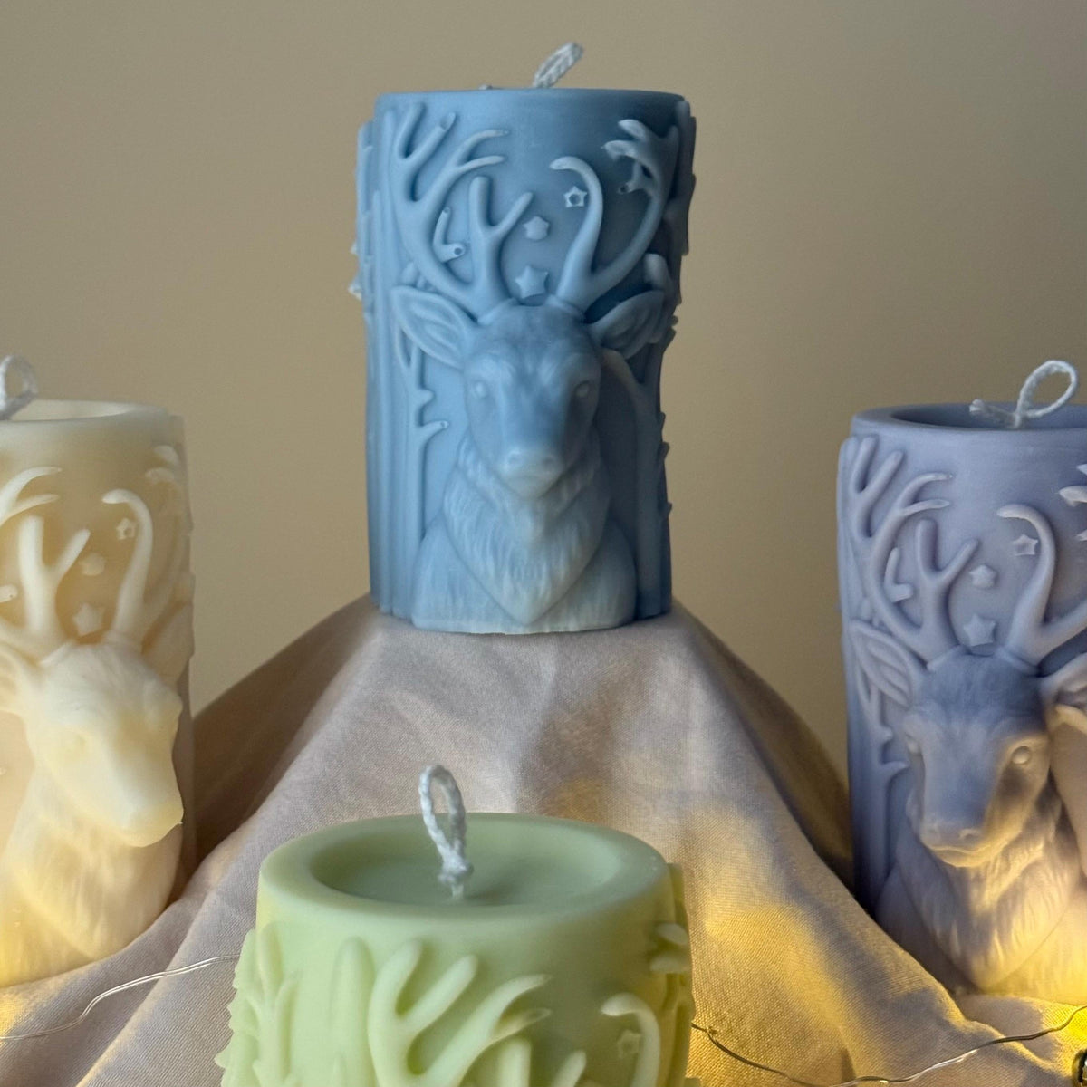 Blue Decorative candles with deer designs on a beige surface