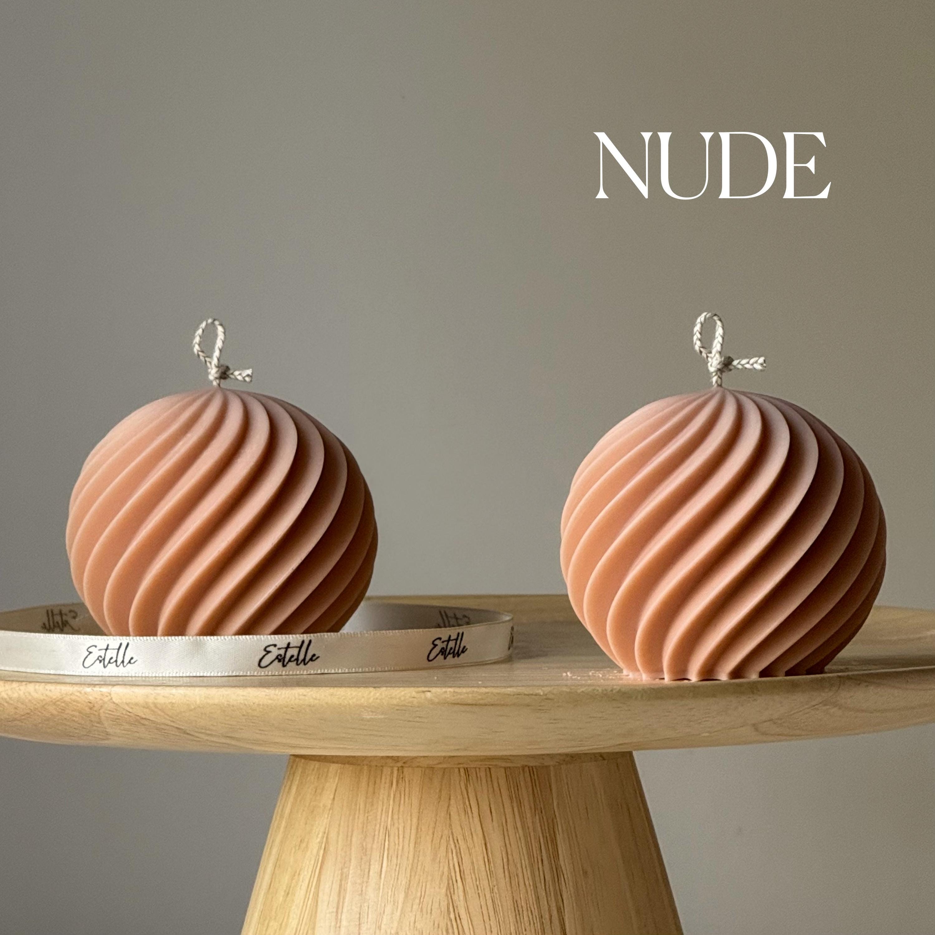 Two nude-colored decorative items on a wooden stand with 'Estelle' branding against a neutral background.