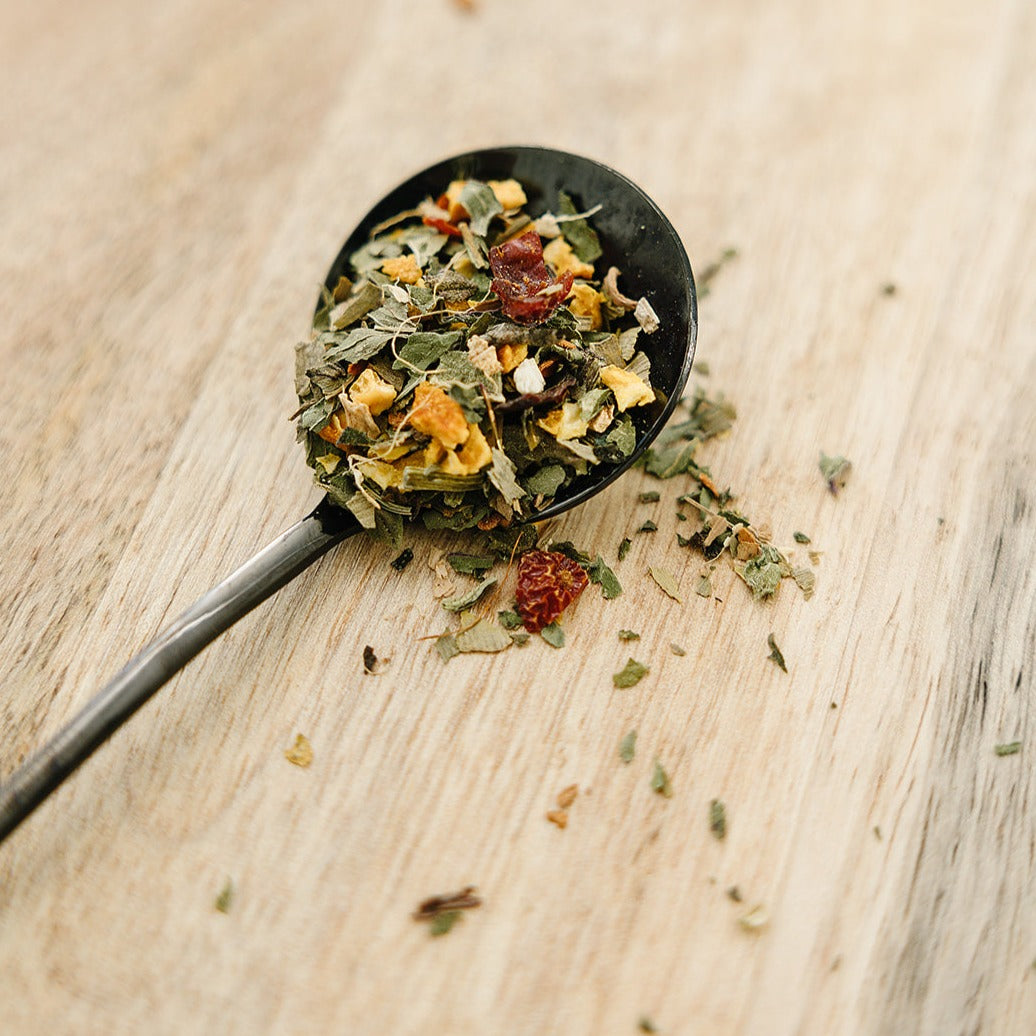Spoonful of dried herbs and spices on a wooden surface