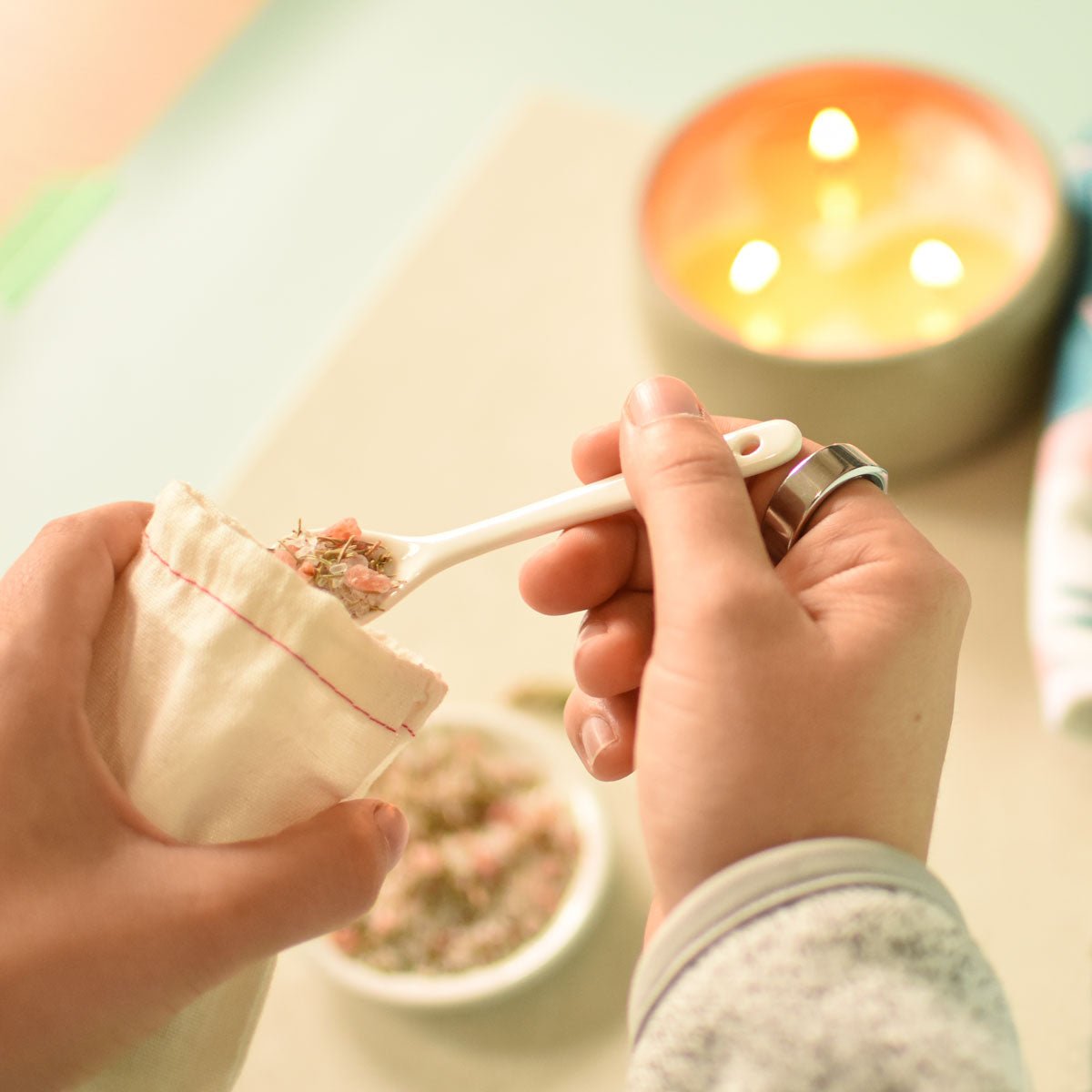 Person holding a small white spoon with a decorative handle over a light-colored surface.