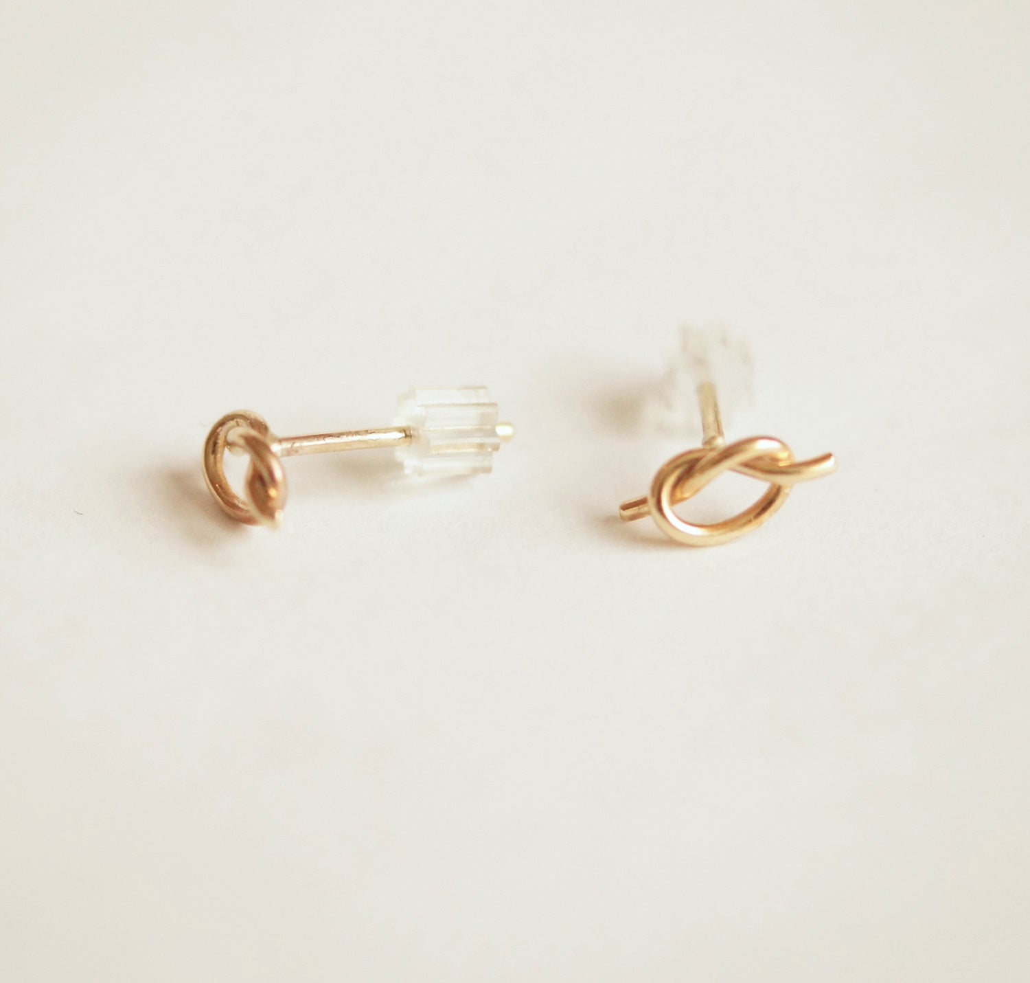 Gold knot earrings on a light beige background