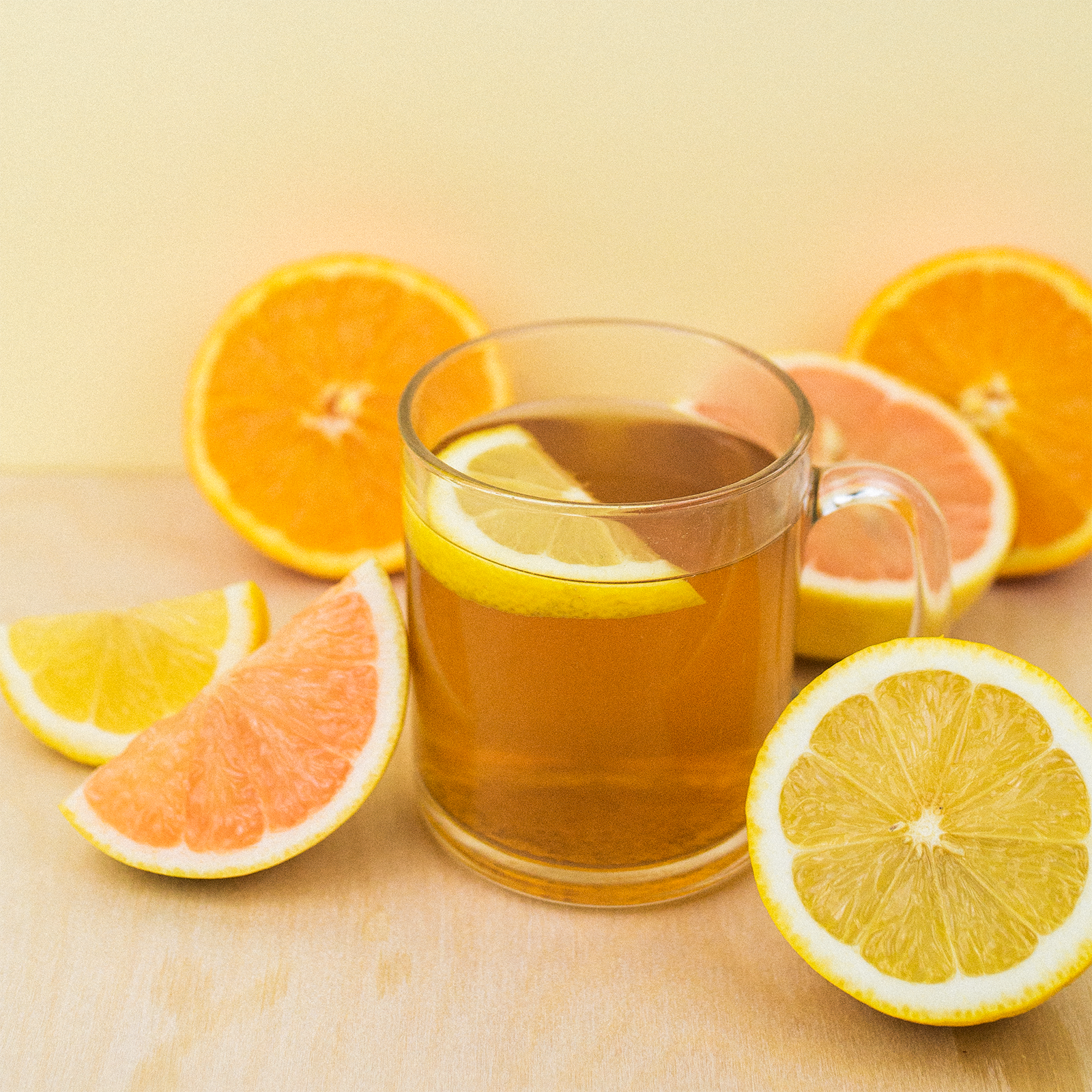 Glass of iced tea with citrus fruits on a yellow background