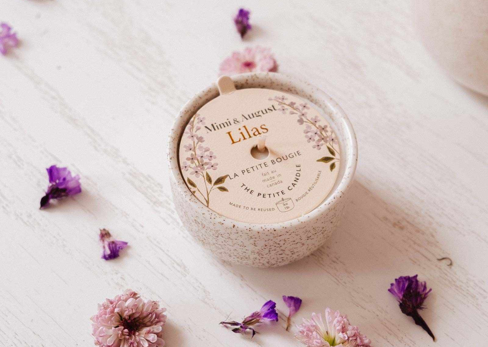 Round container labeled 'Lilas' with scattered flowers on a textured surface mimi-and-august