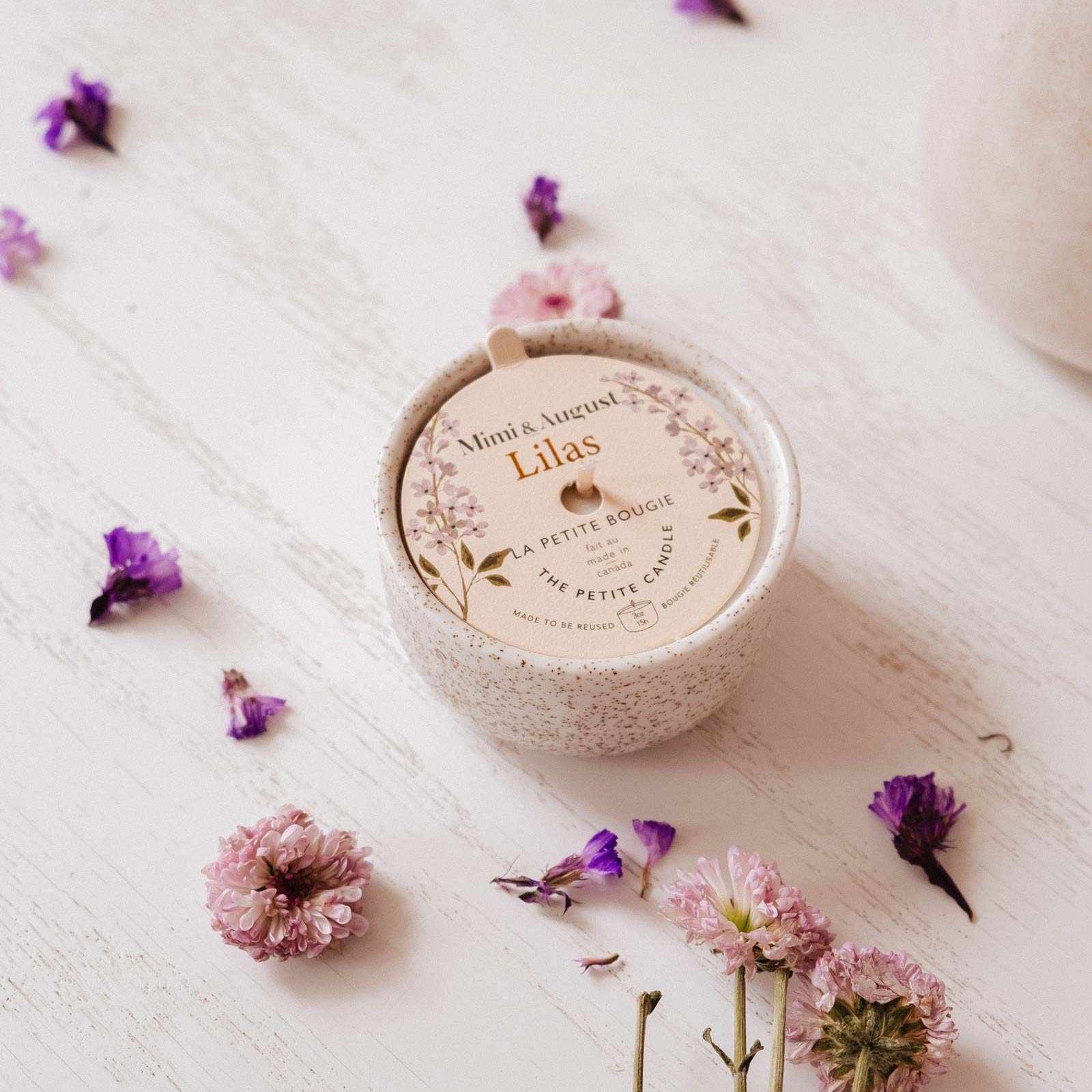 Round container labeled 'Lilas' with scattered flowers on a textured surface mimi-and-august