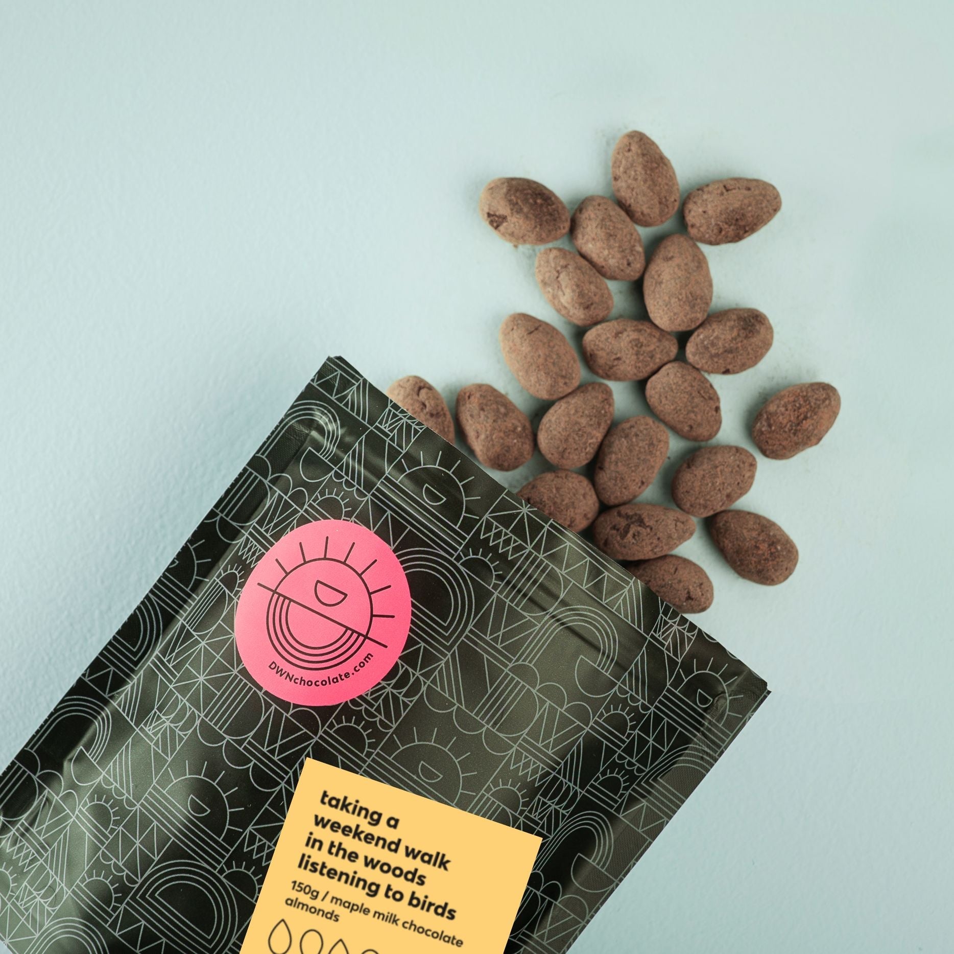 Chocolate almonds on a light blue background with a branded packaging sleeve.