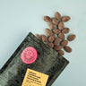 Chocolate almonds on a light blue background with a branded packaging sleeve.