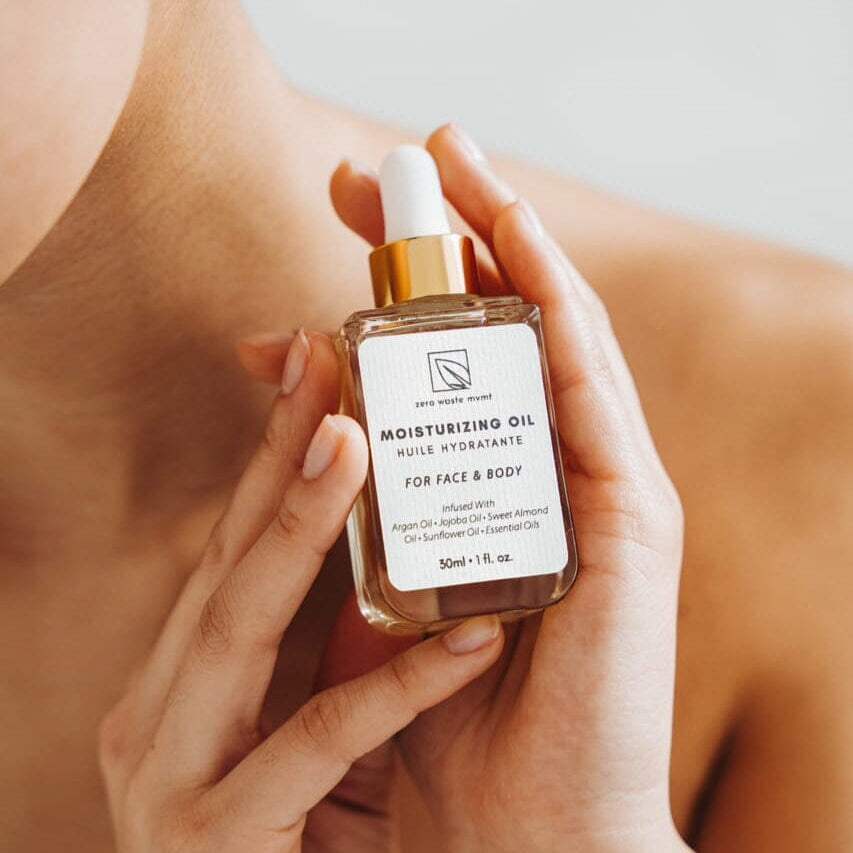 Person holding a bottle of moisturizing oil with a dropper.