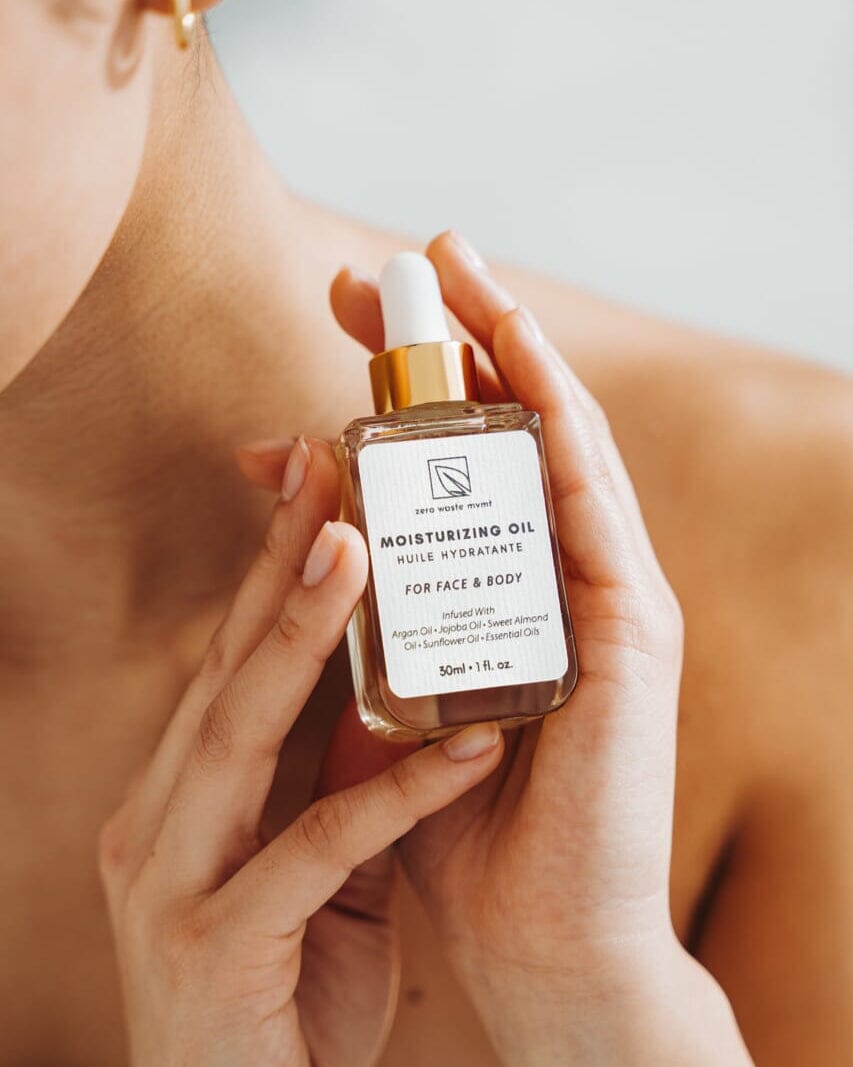 Person holding a bottle of moisturizing oil with a dropper.