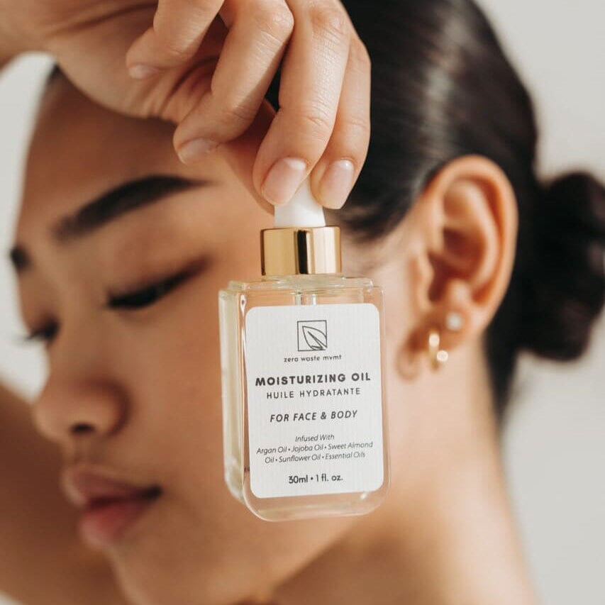 Person holding a bottle of moisturizing oil with a blurred background