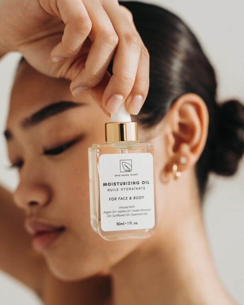 Person holding a bottle of moisturizing oil with a blurred background