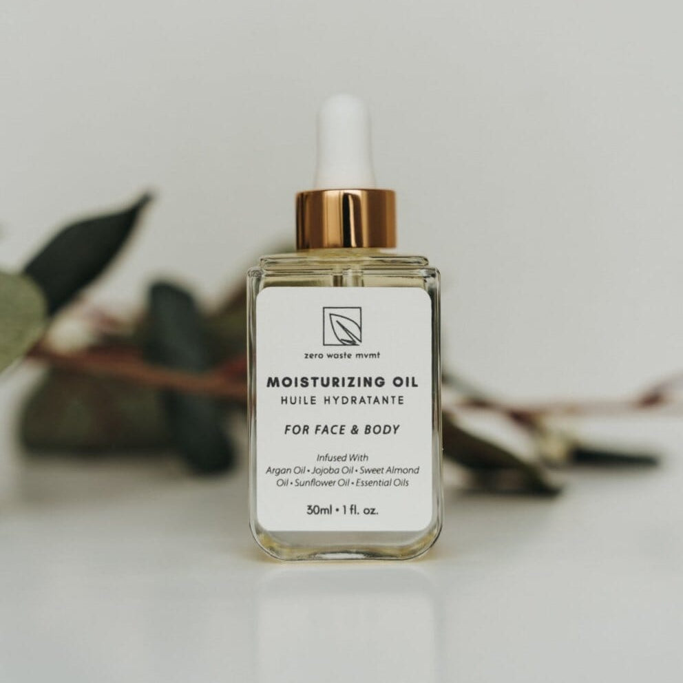 Bottle of moisturizing oil with a white label on a light surface.